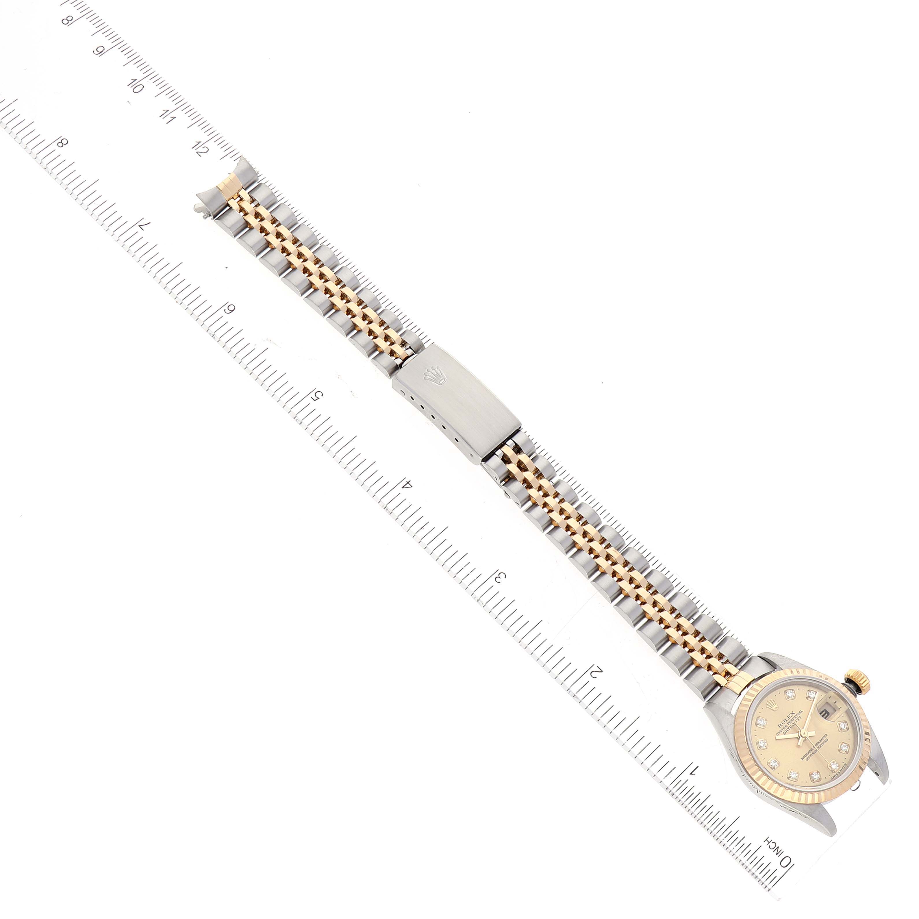 This image shows a Rolex Datejust 79173 Women's Steel and Gold (two tone) Champagne Dial 79173 Women's Steel and Gold (two tone) Champagne Dial watch lying flat, displaying the face, band, and clasp with a ruler alongside for scale.
