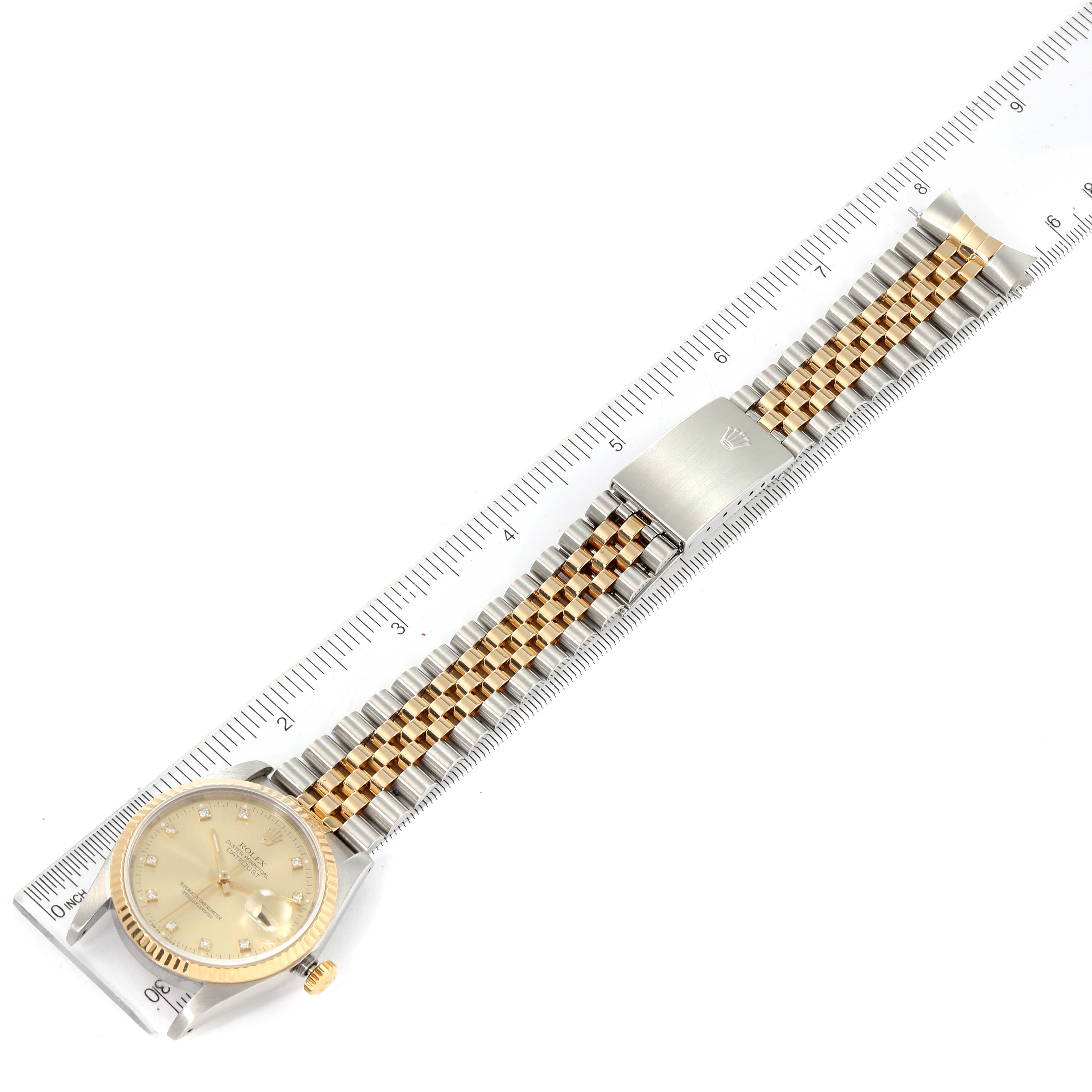 The image shows a Rolex Datejust 16233 Men's Steel and Gold (two tone) Champagne Dial 16233 Men's Steel and Gold (two tone) Champagne Dial watch laid flat on a ruler, displaying its face and two-tone bracelet.