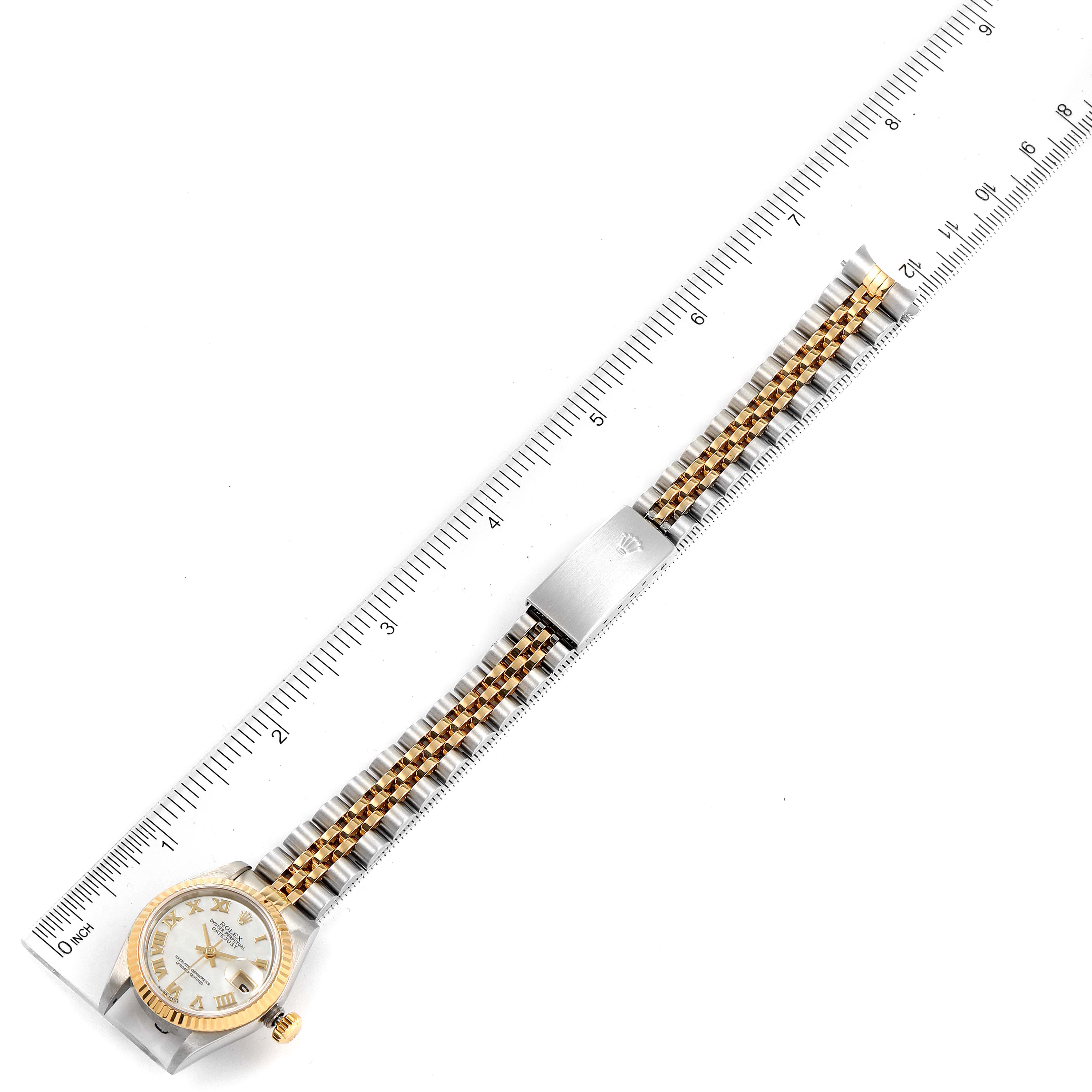 The Rolex Datejust 79173 Women's Steel and Gold (two tone) Mother of Pearl Dial 79173 Women's Steel and Gold (two tone) Mother of Pearl Dial watch is shown in a top-down angle with a ruler, displaying the full face and bracelet.
