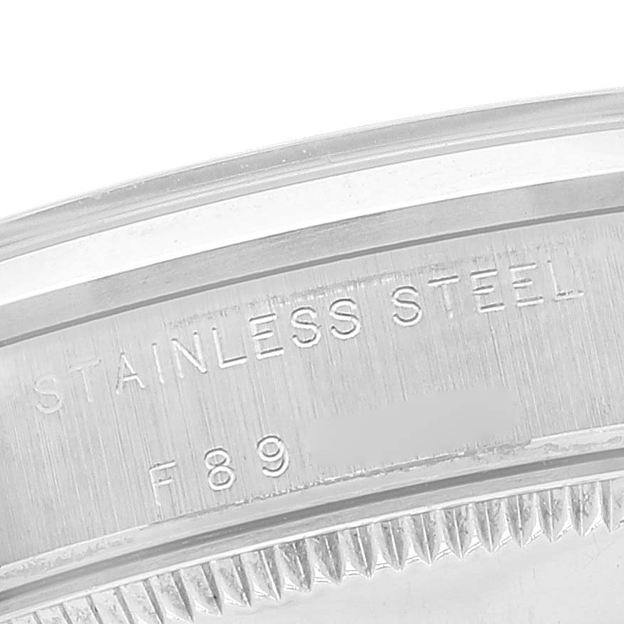 The image shows a close-up of the case back, bezel, and sides of a mid-size Rolex watch, focusing on the "Stainless Steel" engraving.
