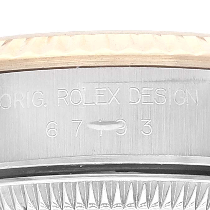 This close-up image shows the side of a Rolex Oyster Perpetual 67193 Women's Steel and Gold (two tone) Champagne Dial 67193 Women's Steel and Gold (two tone) Champagne Dial watch, focusing on the engraved model details.