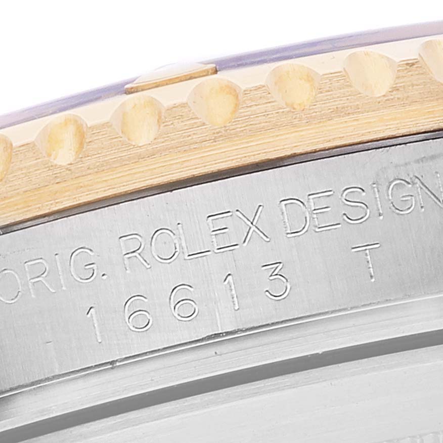 This image shows a close-up of the engraved case of a Rolex Submariner 16613 Men's Steel and Gold (two tone) Blue Dial 16613 Men's Steel and Gold (two tone) Blue Dial, specifically model 16613 T with visible parts of the bezel.