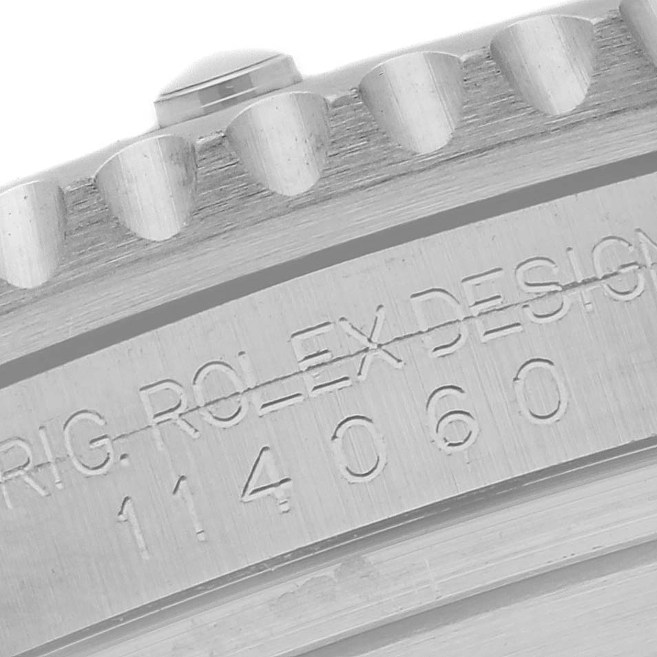 The image shows a close-up of the engraved bezel edge and case side of a Rolex Submariner 114060 Men
s Stainless Steel Black Dial.
