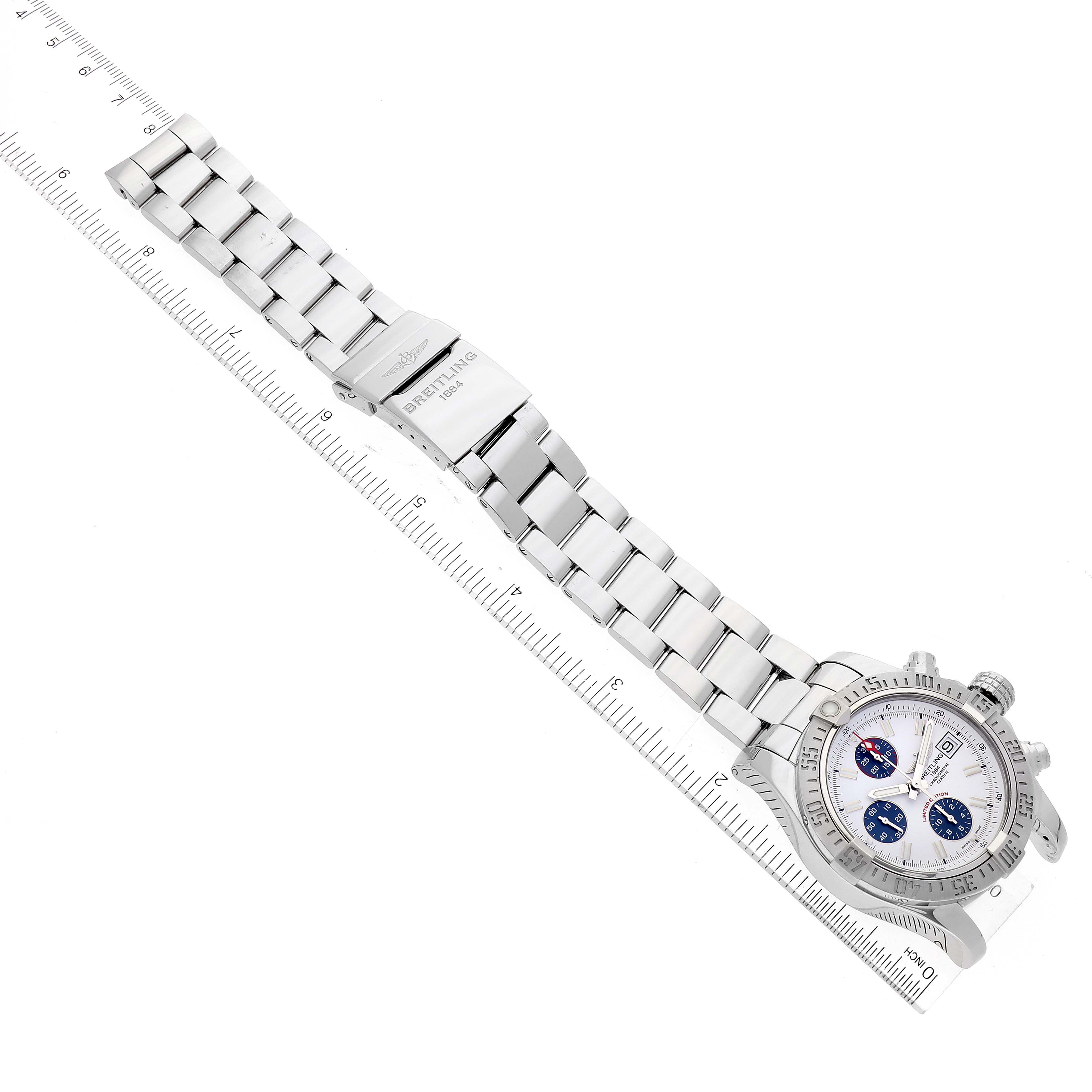 The image shows a Breitling Avenger A13381 Men's Stainless Steel White Dial A13381 Men's Stainless Steel White Dial watch laid flat with a stainless steel bracelet and a ruler for scale.