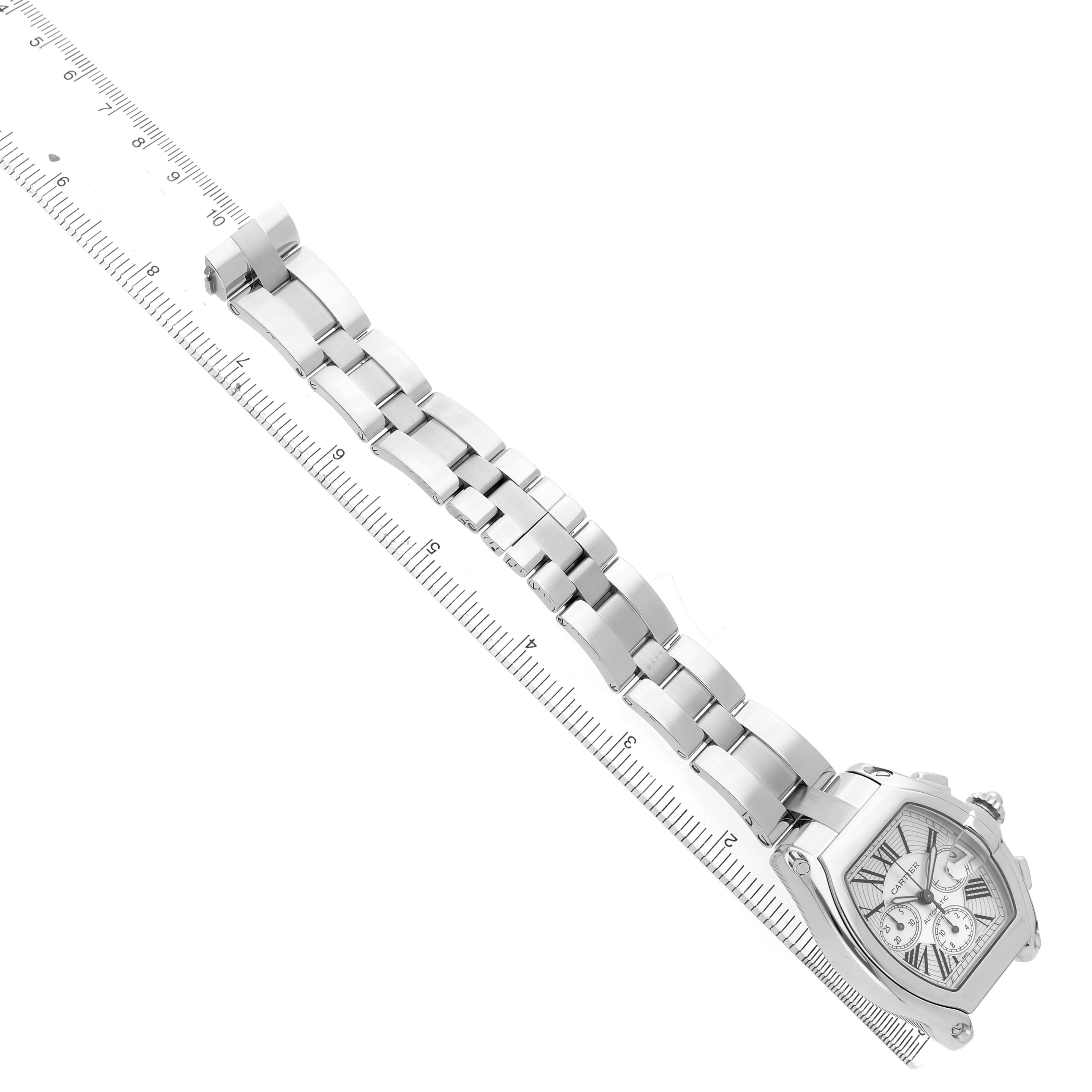 The Cartier Roadster W62019X6 Men's Stainless Steel Silver Dial watch is shown at an angle, displaying the face, bezel, and full bracelet alongside a ruler for size reference.