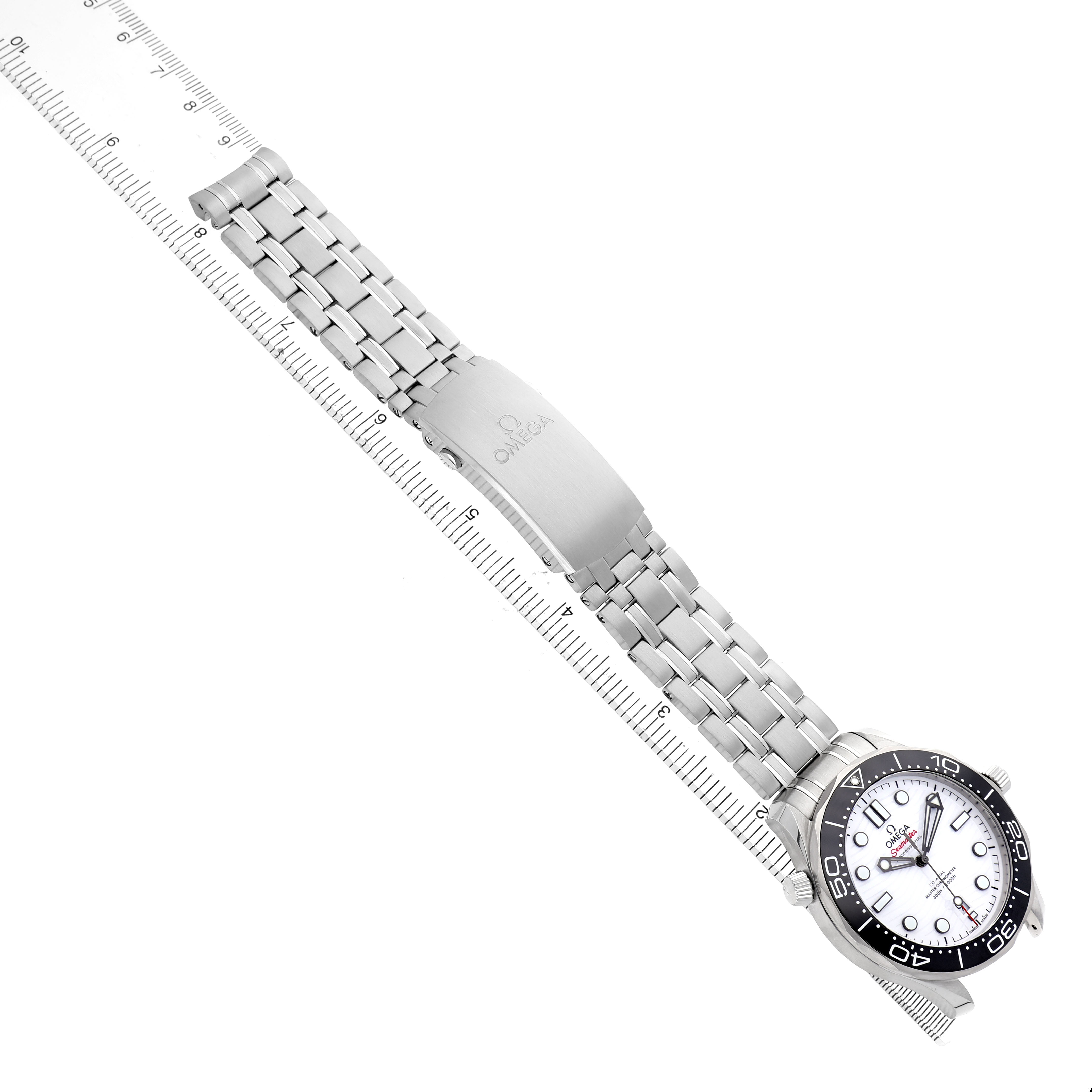 The Omega Seamaster 210.30.42.20.04.001 Men's Stainless Steel White Dial watch is shown from a top-down angle, highlighting its face, bezel, bracelet, and clasp against a ruler background.
