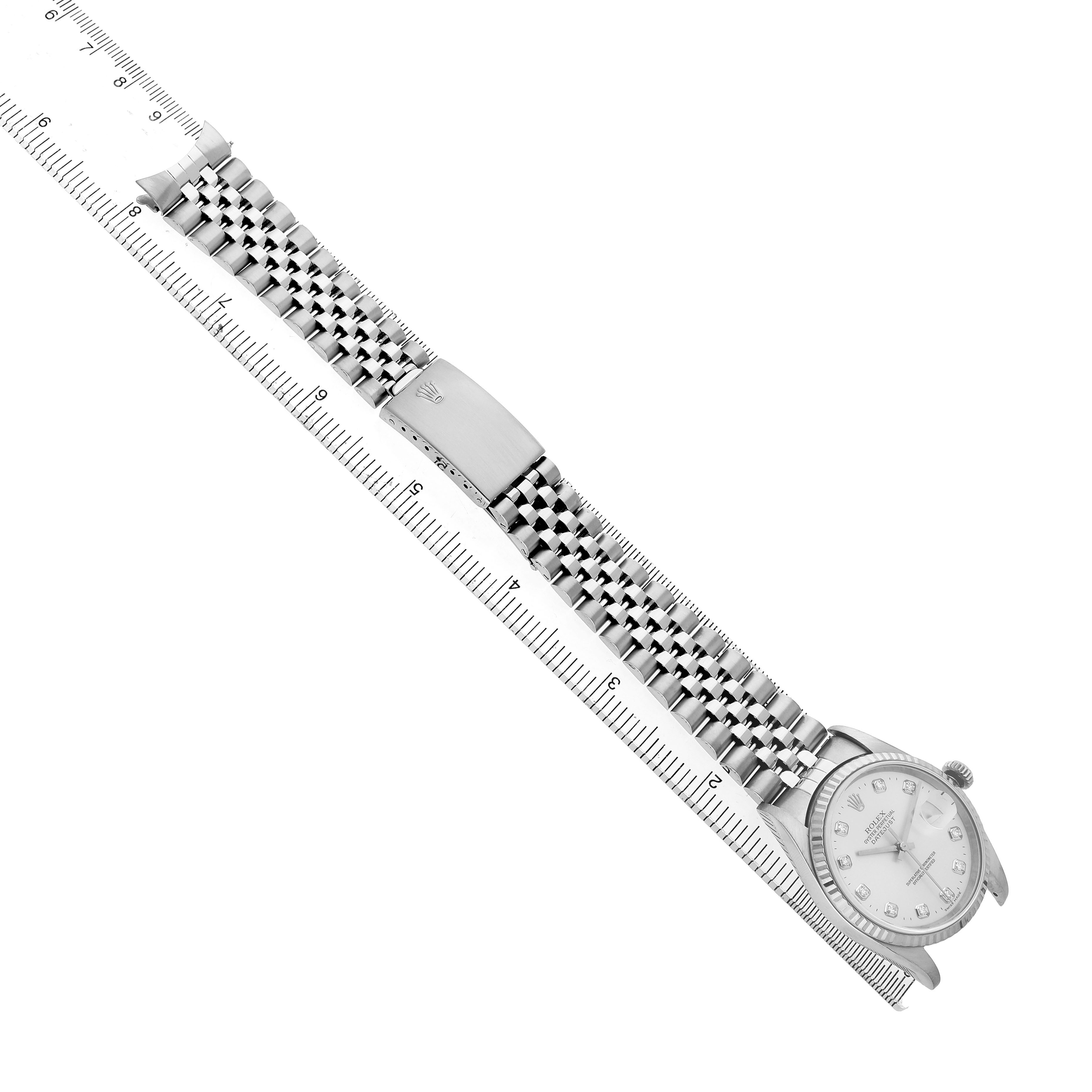 The Rolex Datejust 16234 Men's Stainless Steel Silver Dial watch is shown from a top angle with its full bracelet extended and a clasp visible alongside a ruler.