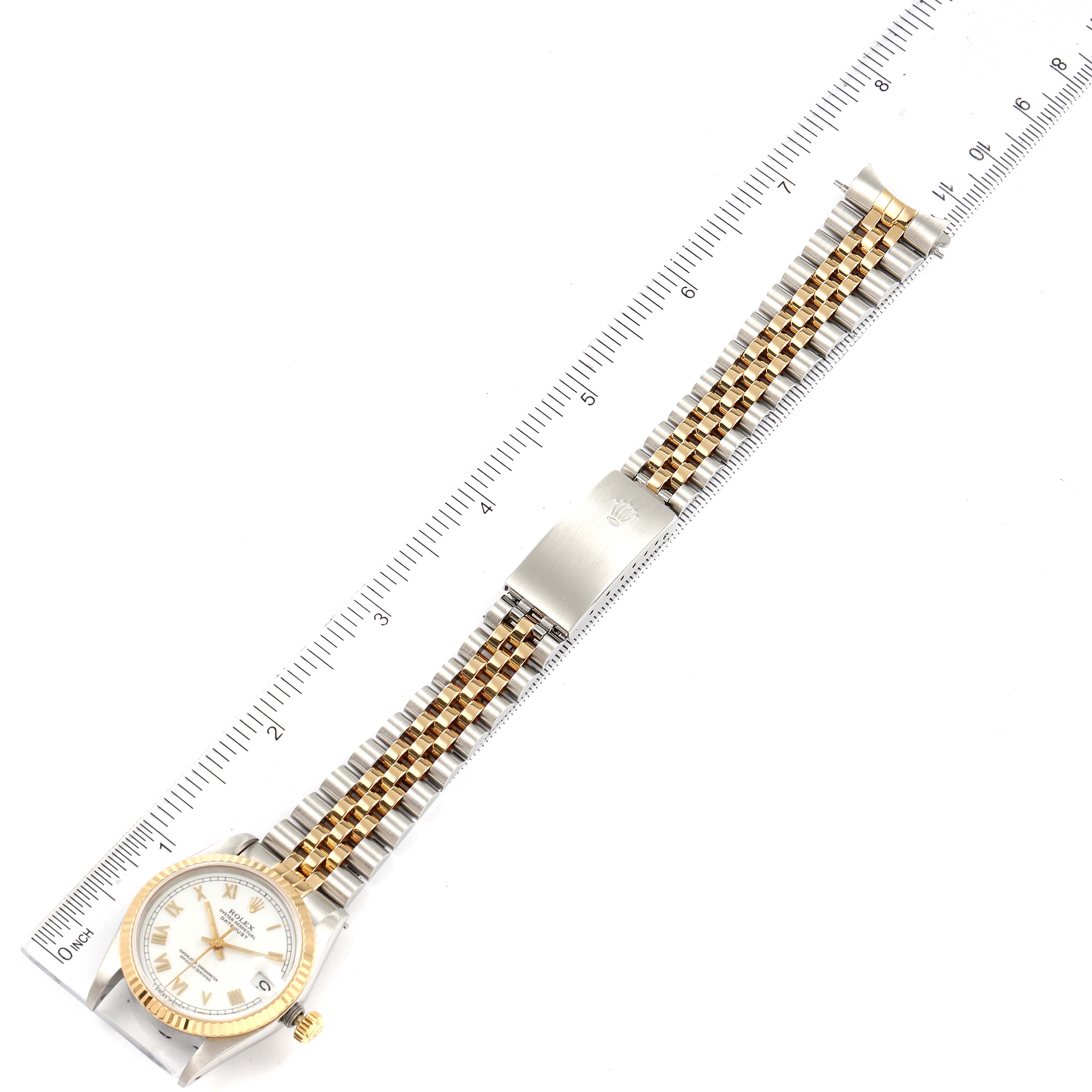 This image shows a top-down view of a Rolex Mid-Size 68273 Women's Steel and Gold (two tone) White Dial 68273 Women's Steel and Gold (two tone) White Dial watch featuring the full band and face alongside a measuring ruler.