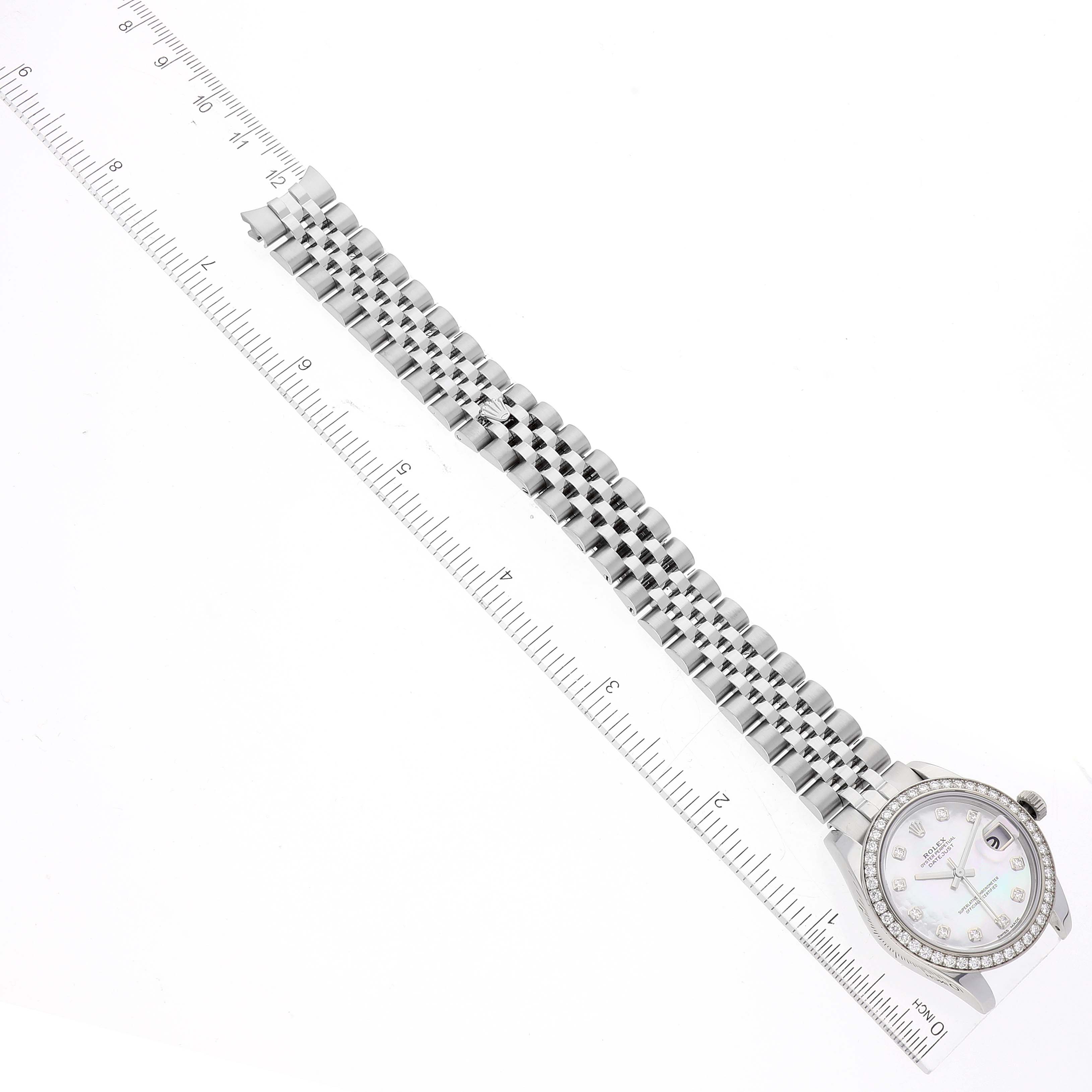 The image shows a top-down view of a Mid-Size Rolex watch with a focus on its bracelet and face, placed alongside a ruler for measurement.