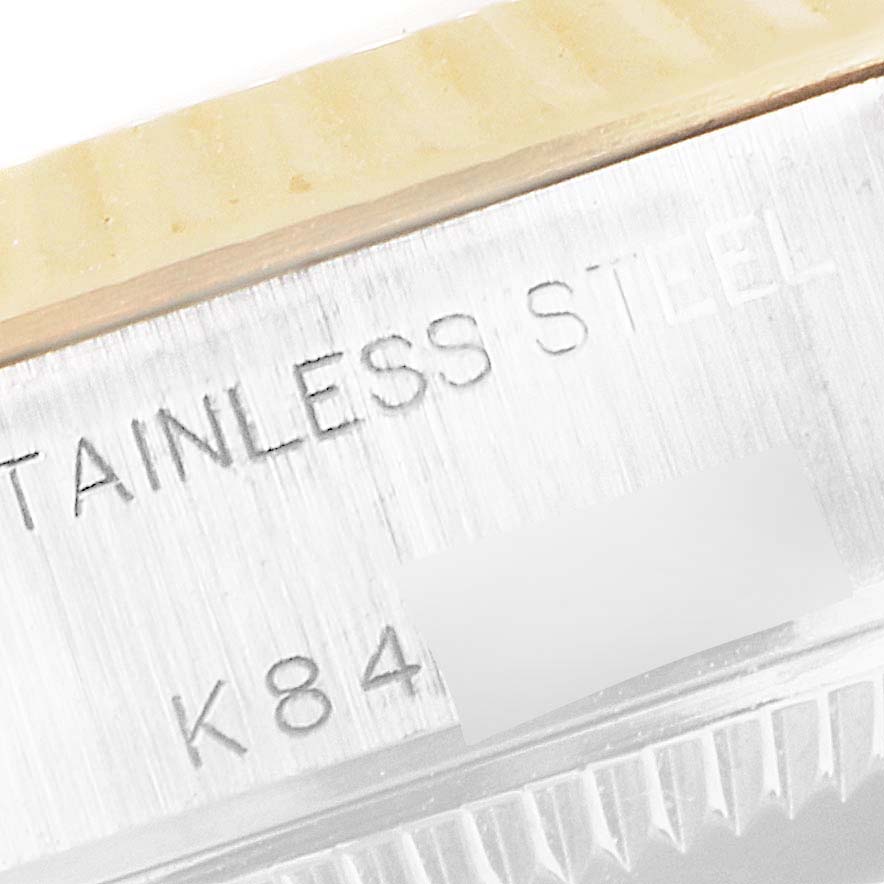 The image shows a close-up of the stainless steel part of a Rolex Datejust 79173 Women's Steel and Gold (two tone) Mother of Pearl Dial 79173 Women's Steel and Gold (two tone) Mother of Pearl Dial watch, including engraving and part of the fluted bezel.