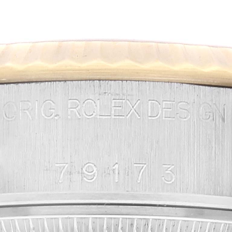 This image shows a close-up of the side of a Rolex Datejust 79173 Women's Steel and Gold (two tone) Champagne Dial 79173 Women's Steel and Gold (two tone) Champagne Dial watch, specifically focusing on the engraved model number and “ORIG. ROLEX DESIGN.”