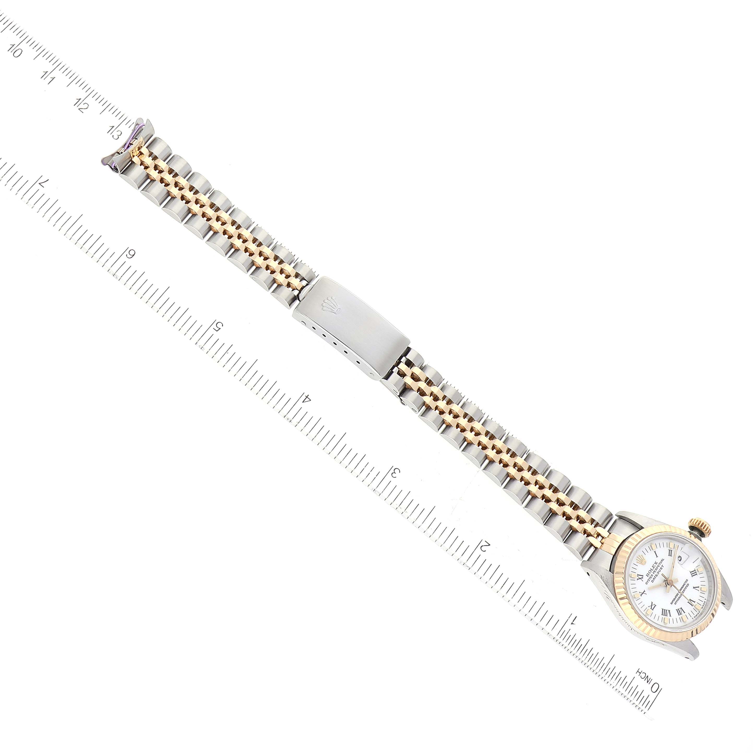 This image shows a bird's-eye view of a Rolex Datejust 69173 Women's Steel and Gold (two tone) White Dial 69173 Women's Steel and Gold (two tone) White Dial watch, including its bracelet, clasp, and face, next to a ruler.