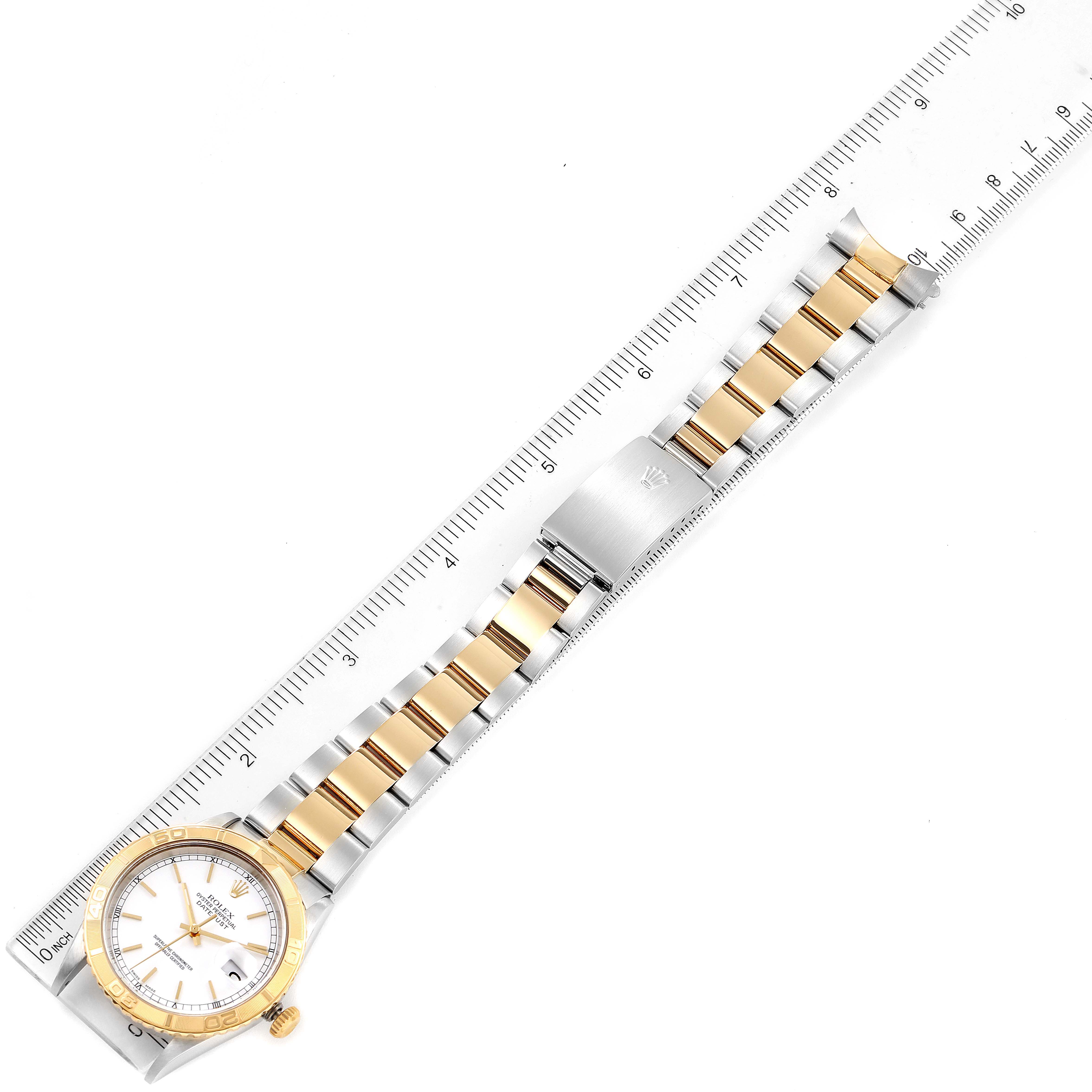 The Rolex Turn-o-Graph 16263 Men
s Steel and Gold (two tone) White Dial 16263 Men
s Steel and Gold (two tone) White Dial watch is shown from the top, displaying the face, entire bracelet, and a clasp beside a ruler.