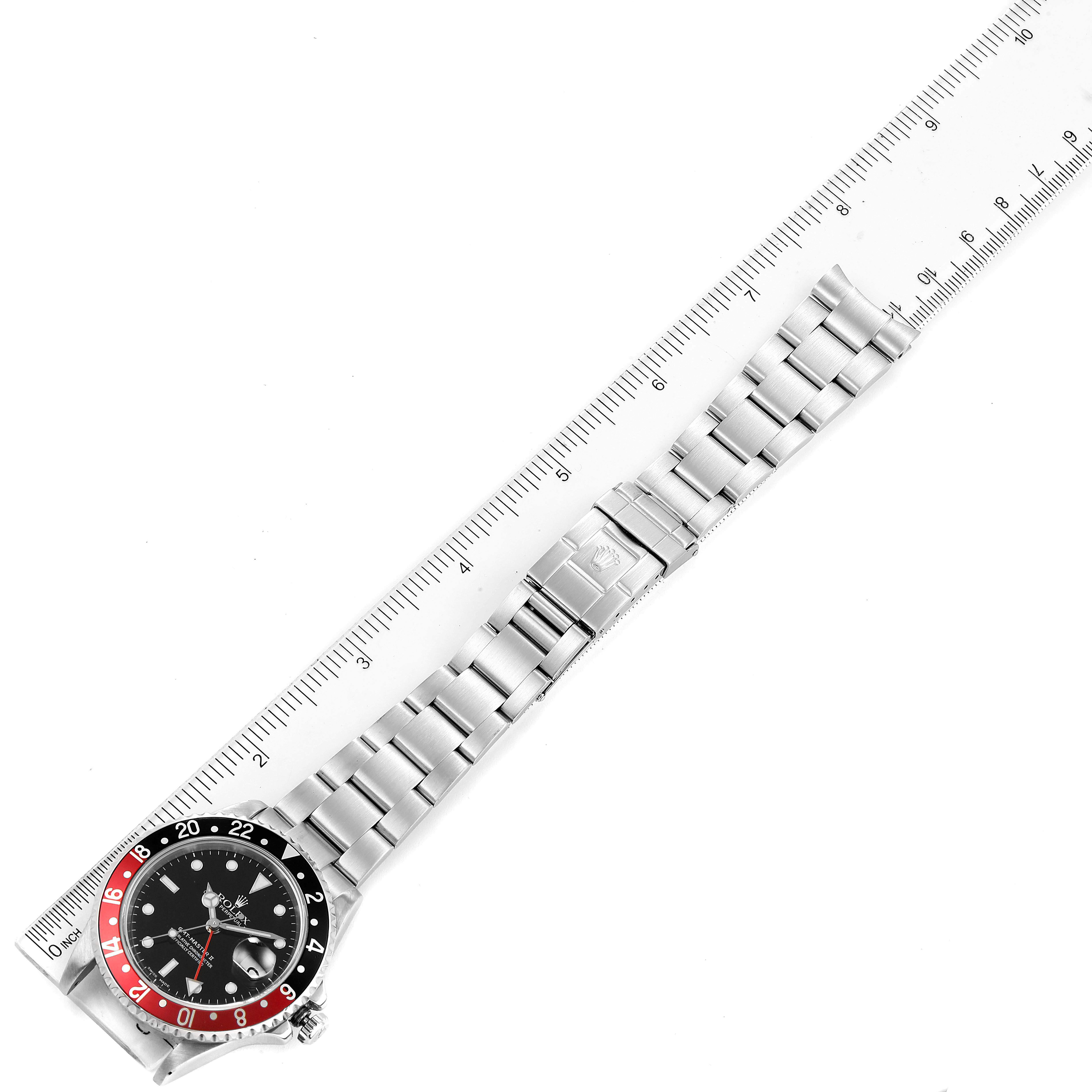 The image shows a top view of a Rolex GMT-Master 16710 Men
s Stainless Steel Black Dial 16710 Men
s Stainless Steel Black Dial watch, displaying the face, bezel, and metal bracelet aligned next to a ruler.
