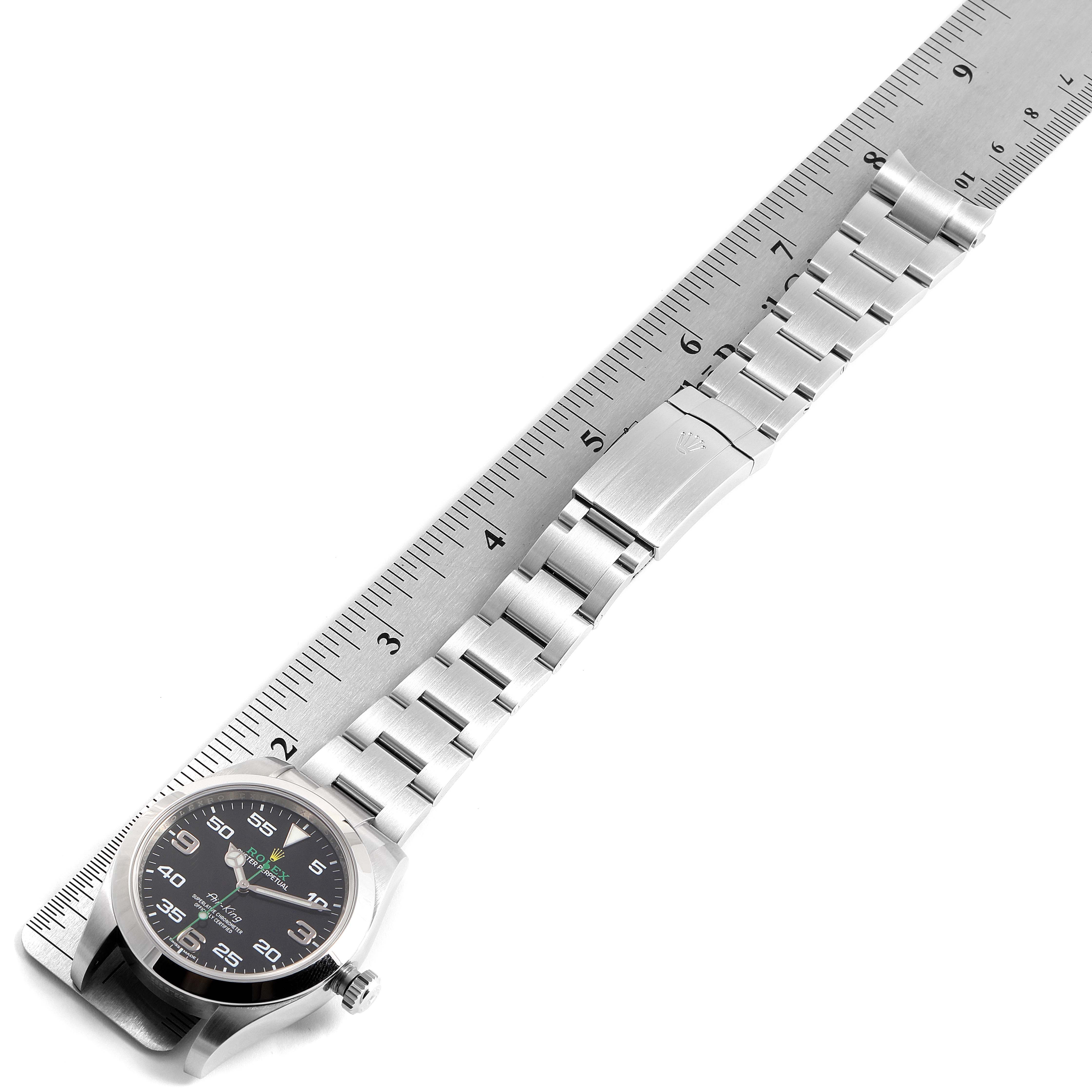 The Rolex Air-King 116900 Men's Stainless Steel Black Dial 116900 Men's Stainless Steel Black Dial watch is shown lying flat next to a ruler, highlighting the face, bezel, and bracelet.