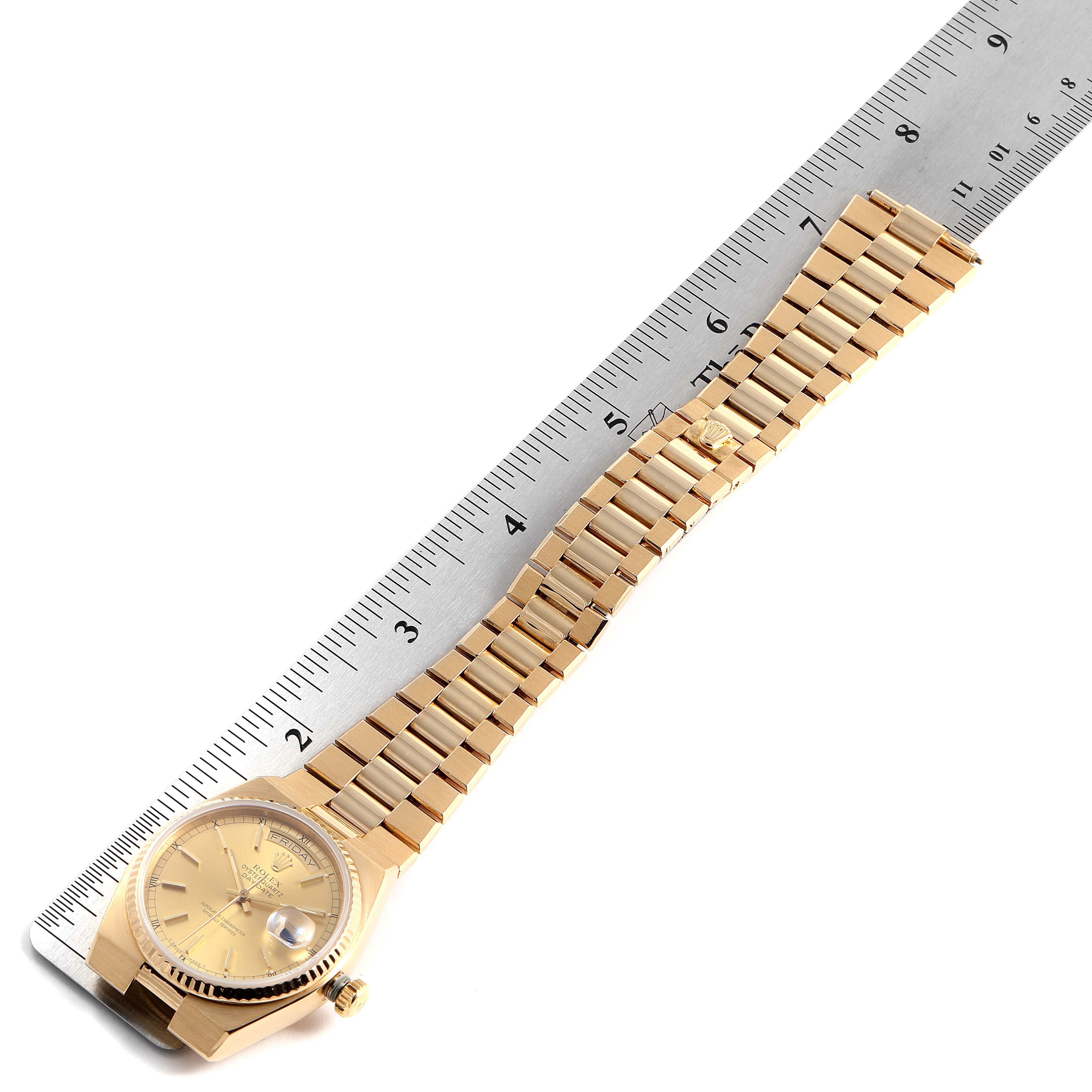 The image shows a Rolex Oysterquartz 19018 Men's Yellow Gold Champagne Dial 19018 Men's Yellow Gold Champagne Dial watch laid flat next to a ruler, displaying the watch face and full bracelet.