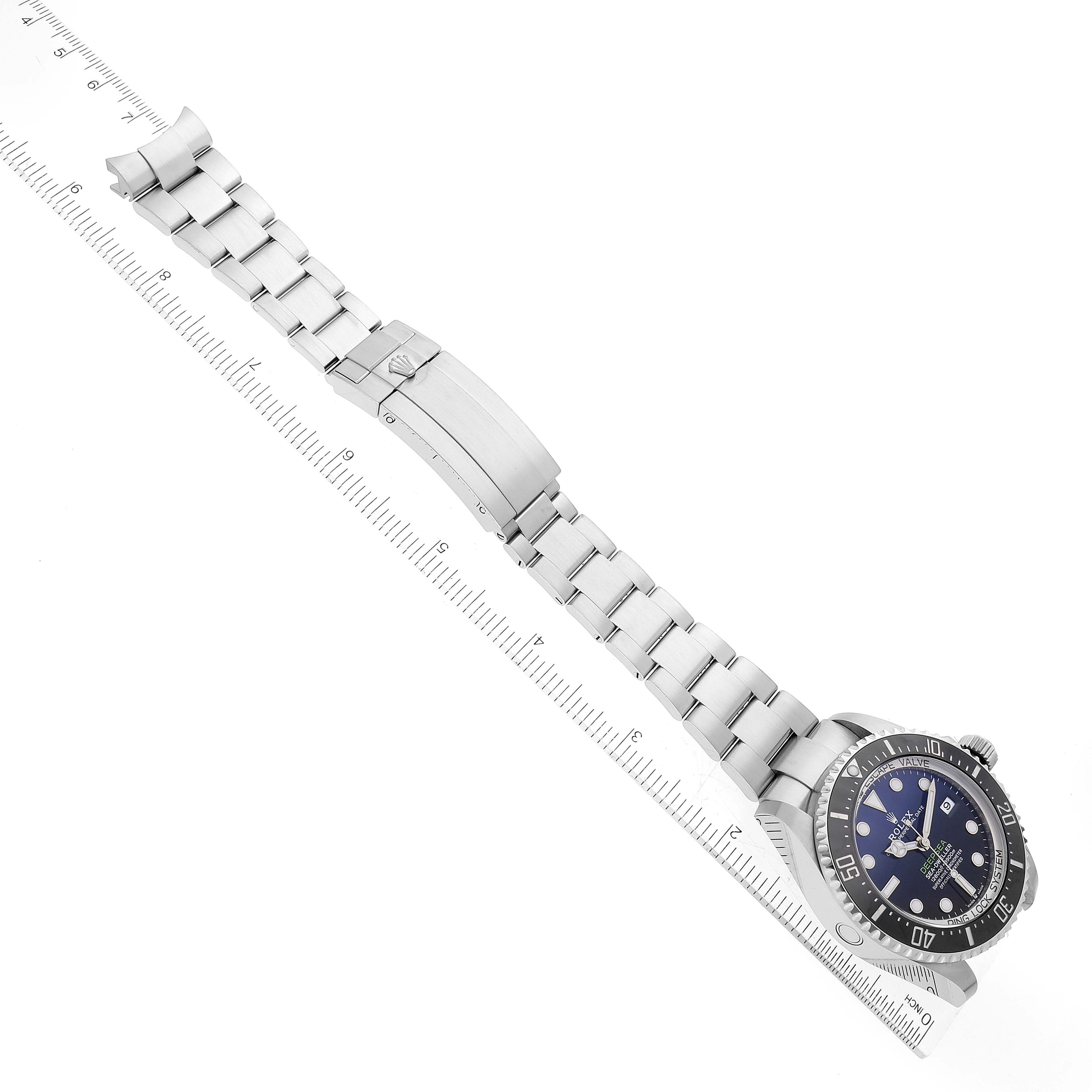 The image shows the front view of a Rolex Sea-Dweller 136660 Men's Stainless Steel Blue Dial 136660 Men's Stainless Steel Blue Dial watch with its full metal bracelet and clasp, accompanied by a ruler for scale.