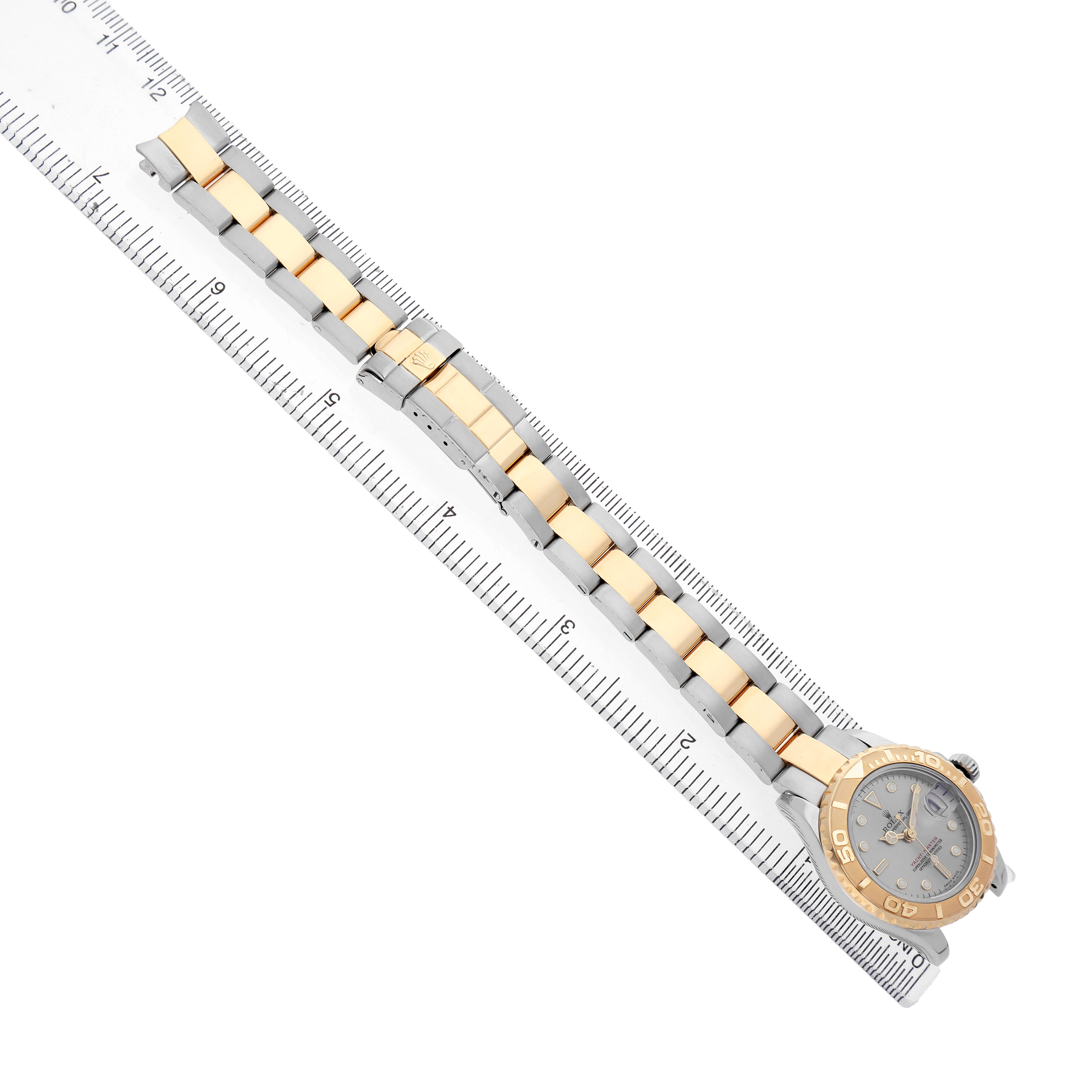 The Rolex Yacht-Master 169623 Women's Steel and Gold (two tone) Grey Dial watch is shown from a top-down angle, displaying its face and two-tone bracelet alongside a ruler for scale.