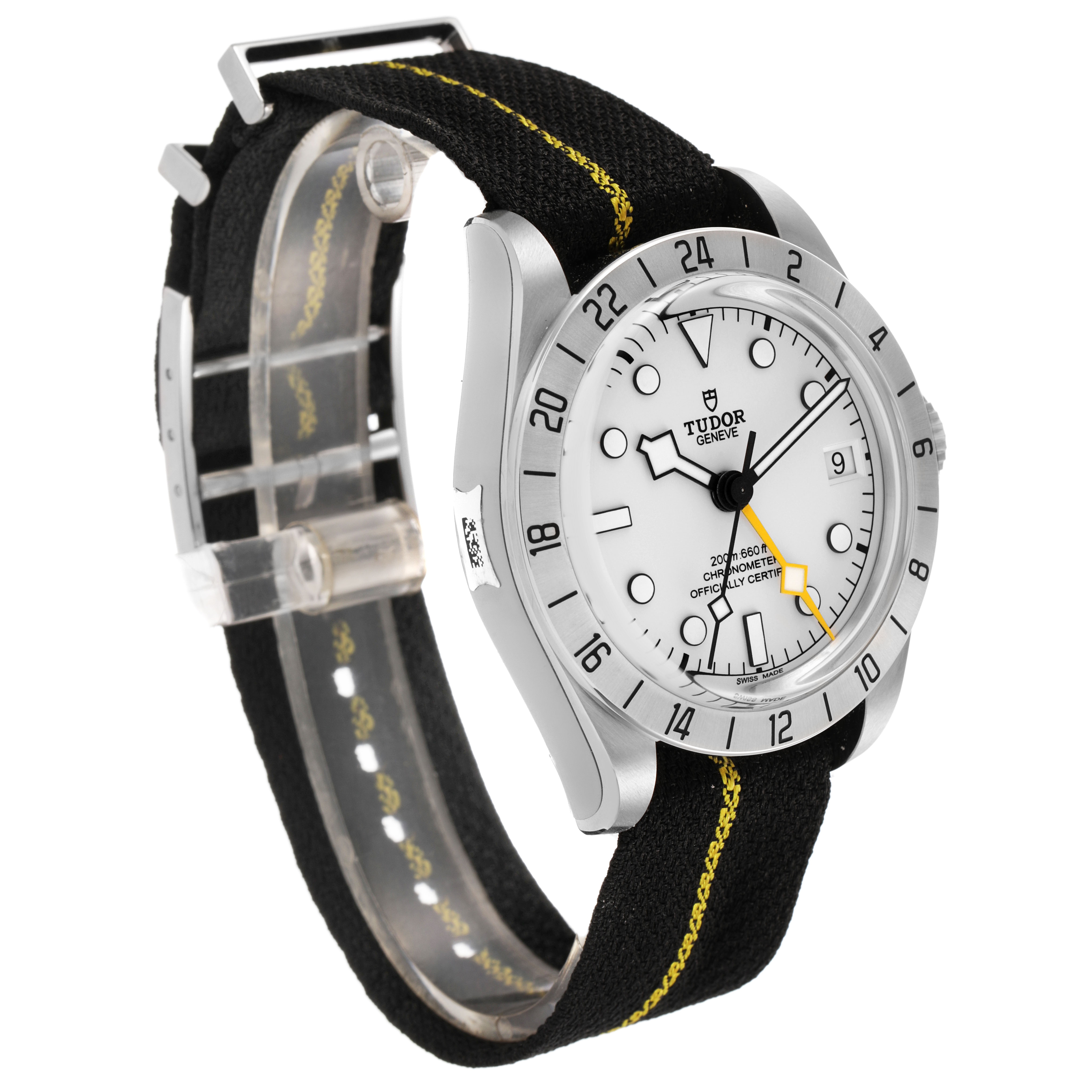 The Tudor Heritage Black Bay 79470 Men's Stainless Steel Black Dial watch is shown at a three-quarter angle, highlighting its face, bezel, and fabric strap.