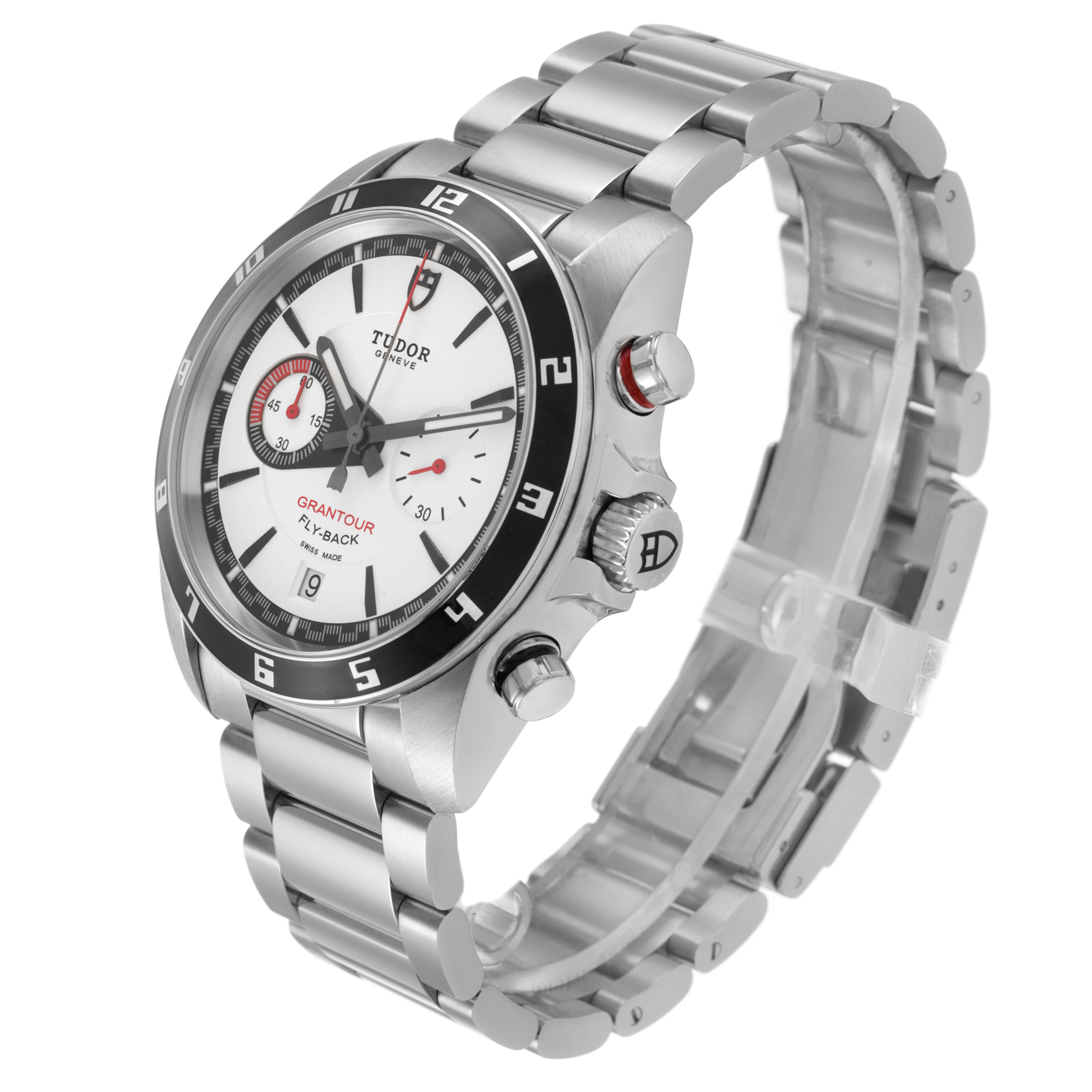 The Tudor watch is a Glamour model, shown at a three-quarter angle highlighting the face, bezel, crown, and stainless steel bracelet.