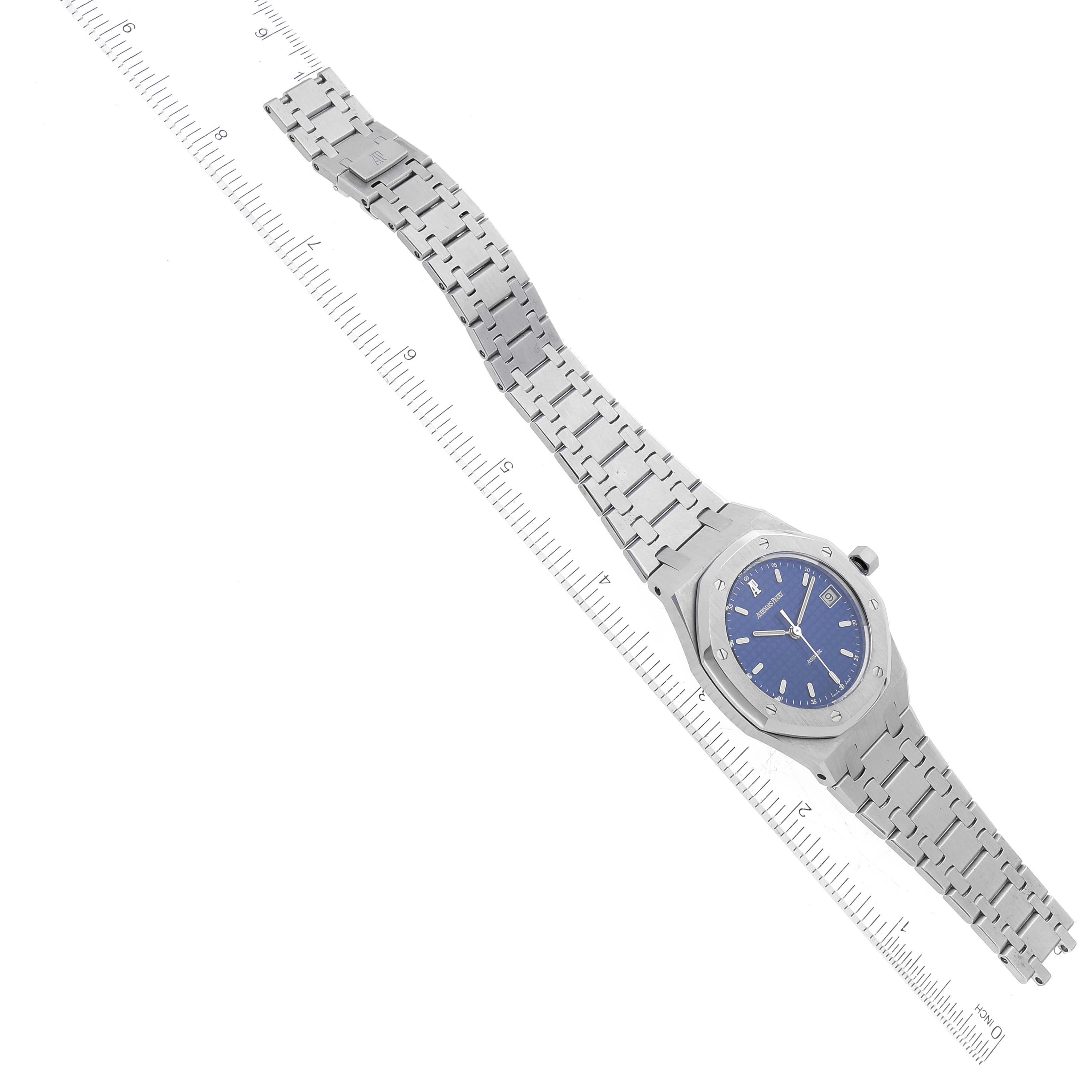 The image shows a top-down view of an Audemars Piguet Royal Oak 14790ST.OO.0789ST.08 Men's Stainless Steel Blue Dial 14790ST.OO.0789ST.08 Men's Stainless Steel Blue Dial watch with a blue dial and a stainless steel bracelet, alongside a ruler for scale.