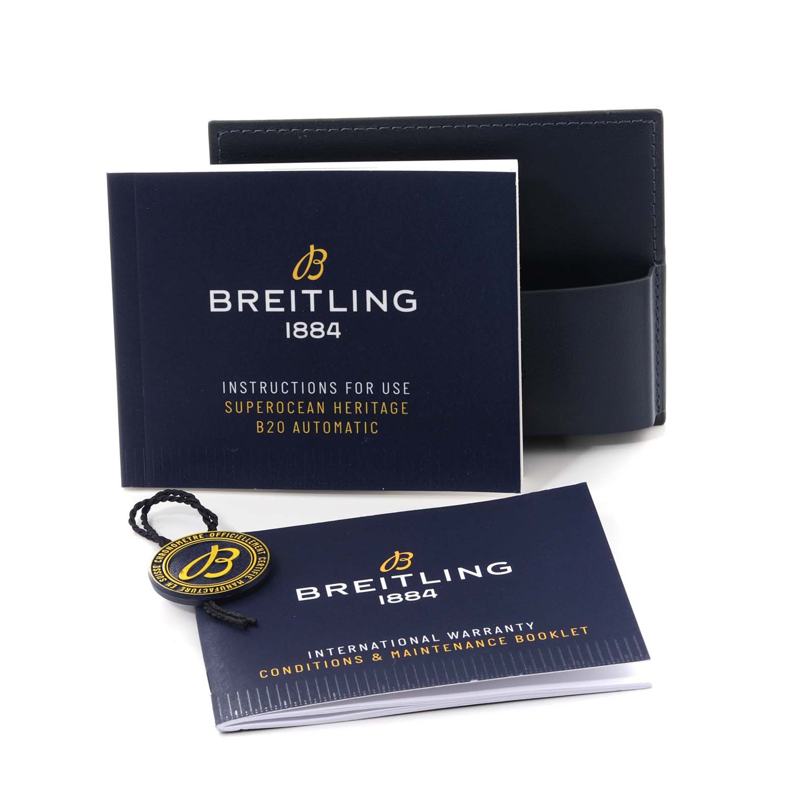 The image shows accessories for the Breitling Superocean UB2030121B1A1 Men's Steel and Gold (two tone) Black Dial UB2030121B1A1 Men's Steel and Gold (two tone) Black Dial model, including instruction booklets, a warranty booklet, and a tag.