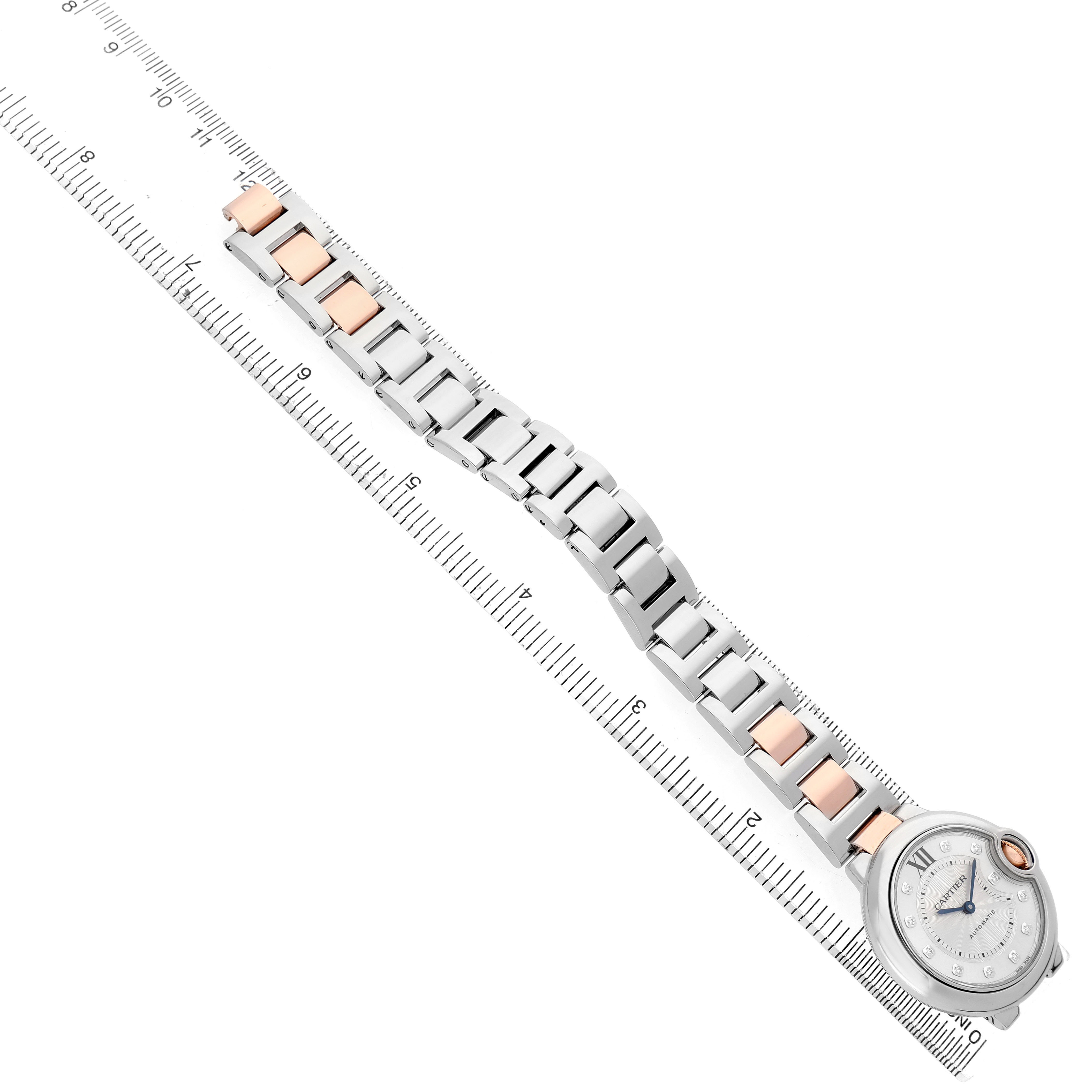The Cartier Ballon Bleu WE902044 Women's Steel and Gold (two tone) Silver Dial watch is shown at a tilted angle, highlighting the face and bracelet alongside a ruler.