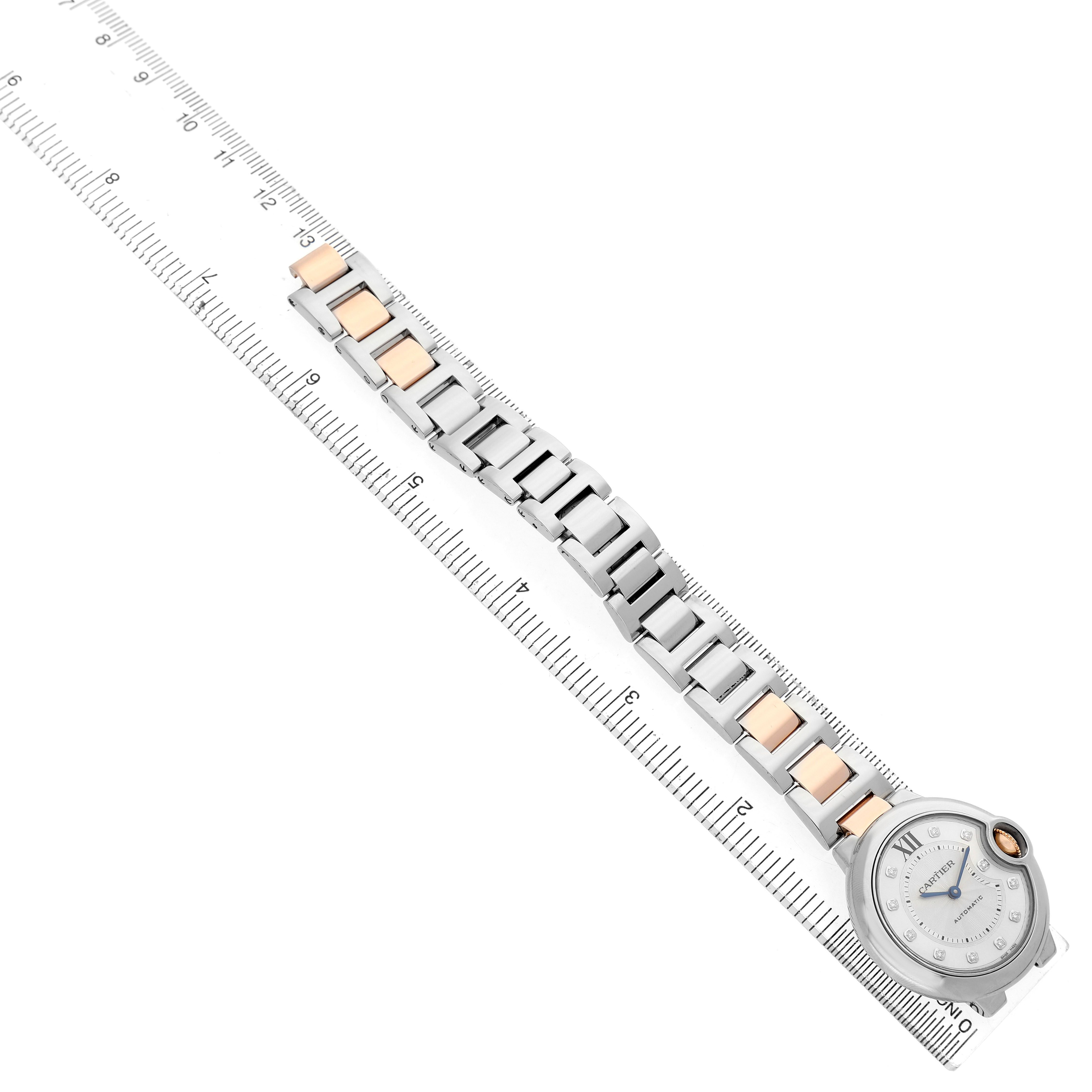 The Cartier Ballon Bleu WE902061 Women's Steel and Gold (two tone) Silver Dial watch is shown at an angle, highlighting the face, bracelet, and a ruler for size reference.