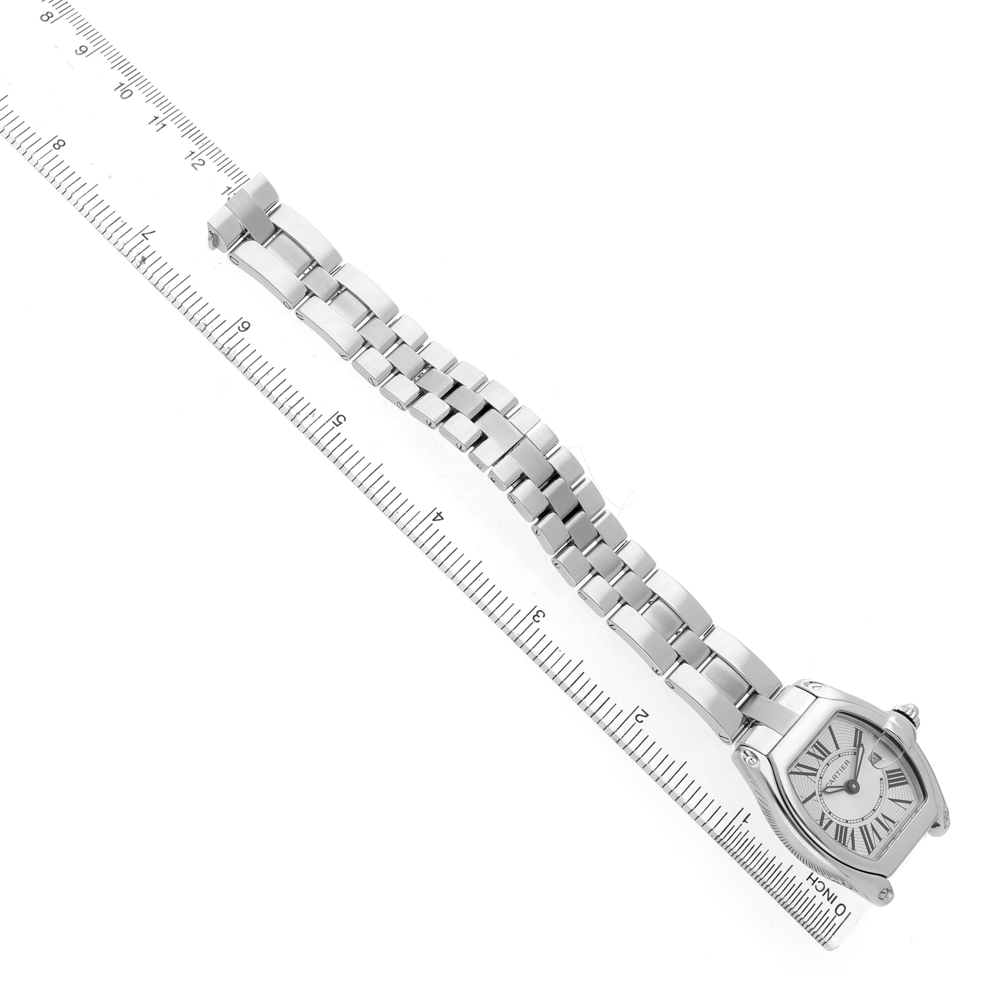 The Cartier Roadster W62016V3 Women's Stainless Steel Silver Dial watch is shown diagonally from above, featuring its case, bracelet, and part of a ruler for scale.