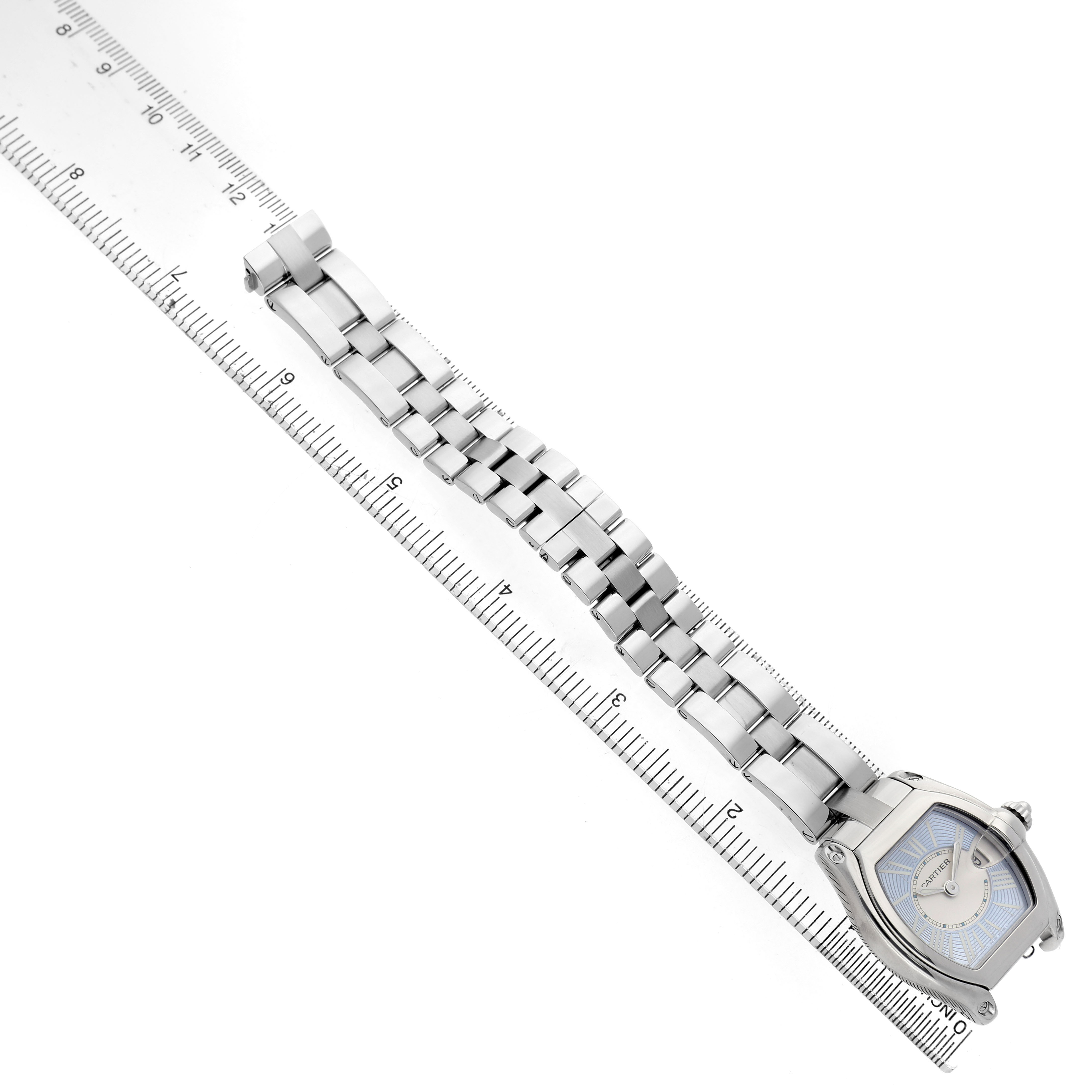 The Cartier Roadster W62053V3 Women's Stainless Steel Blue Dial watch is shown at an angled top view, highlighting its bracelet and face next to a ruler for scale.