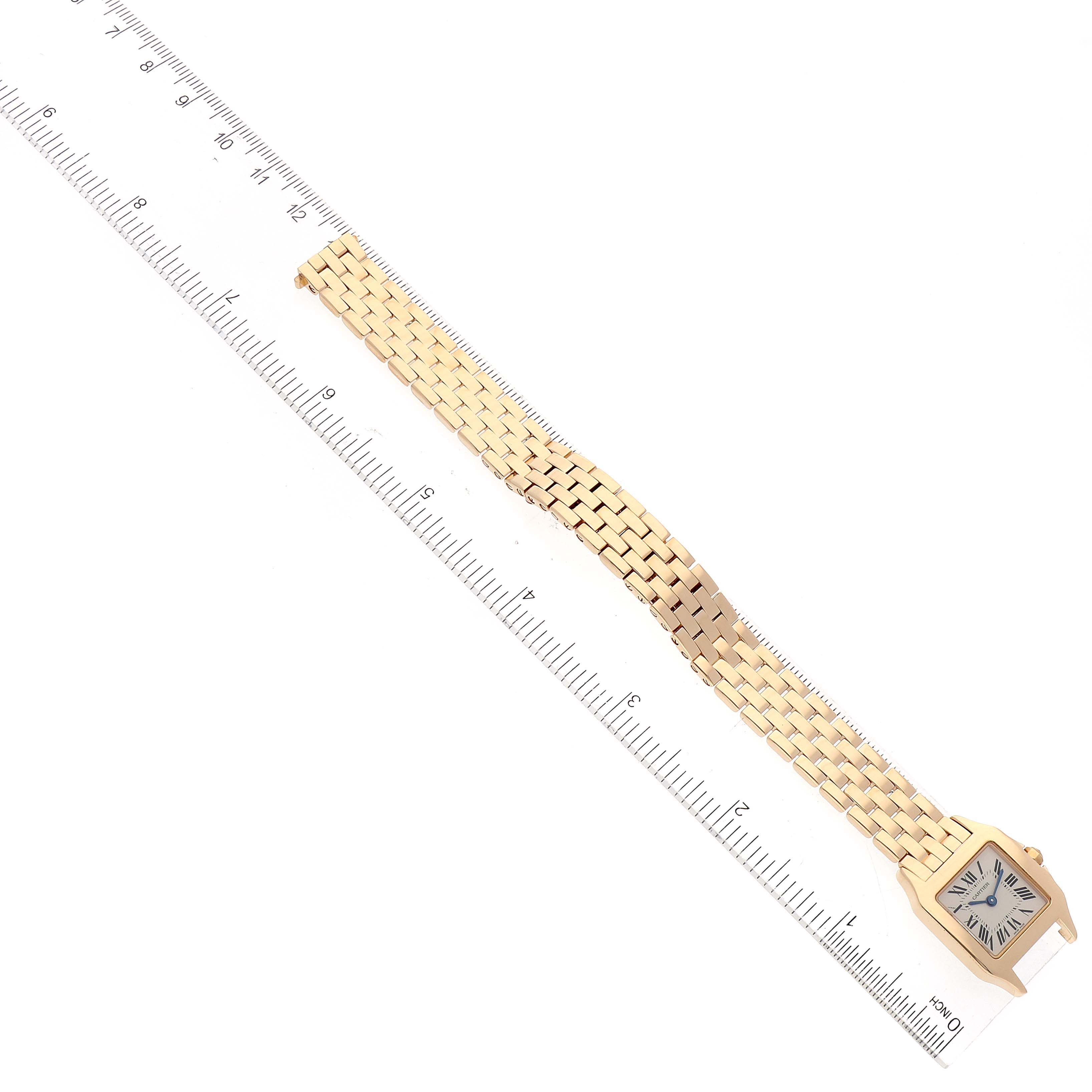 The image shows the Cartier Santos Demoiselle W25063X9 Women's Yellow Gold Silver Dial W25063X9 Women's Yellow Gold Silver Dial watch lying flat with its golden bracelet and case placed next to a ruler for scale.