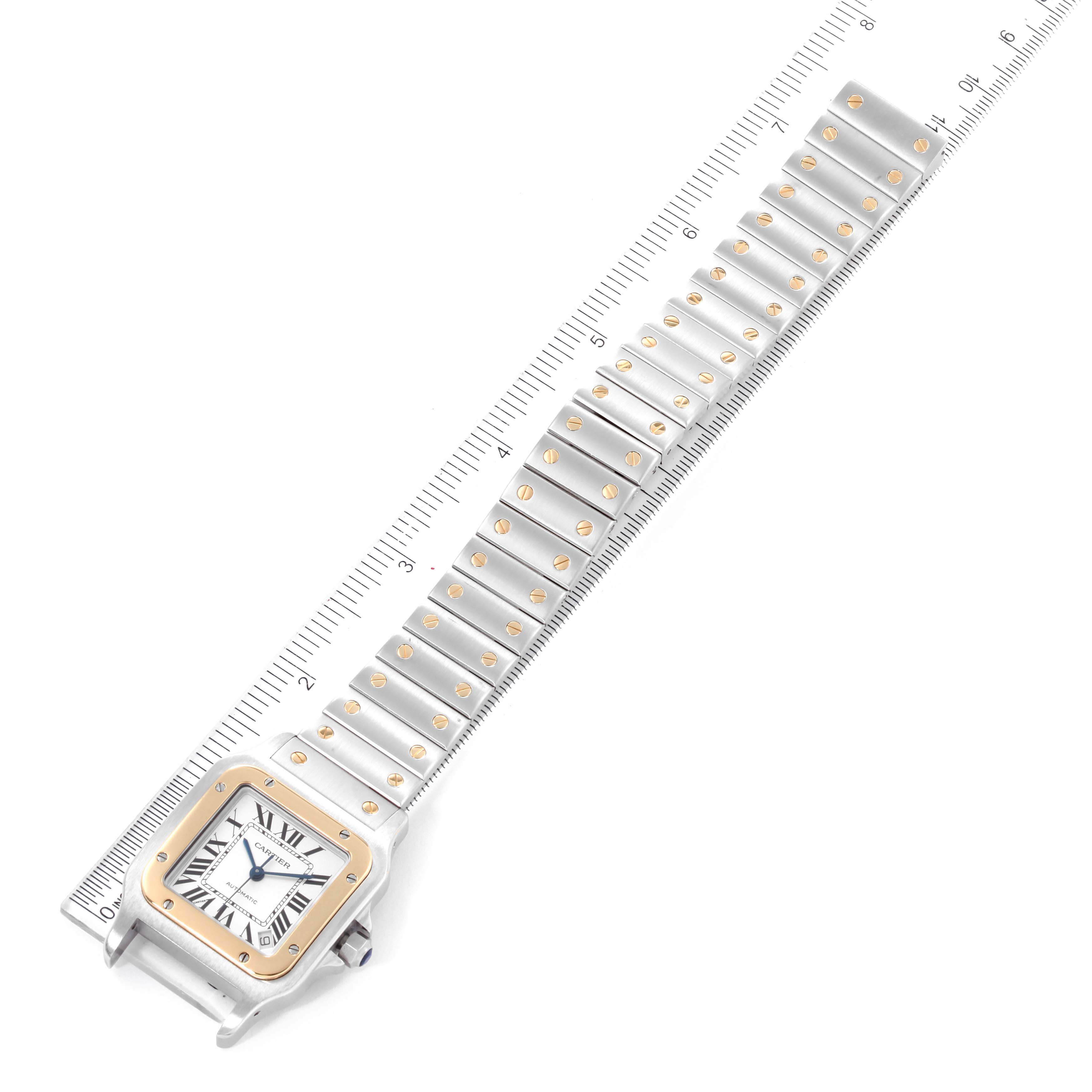The image shows a top view of a Cartier Santos W20099C4 Men
s Steel and Gold (two tone) Silver Dial W20099C4 Men
s Steel and Gold (two tone) Silver Dial watch, showcasing its square face, bezel, and full metal bracelet next to a ruler.