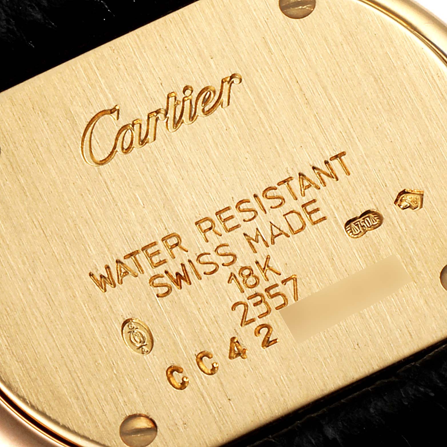 The image shows a close-up of the case back of a Trinity model by Cartier, highlighting its engravings and markings.