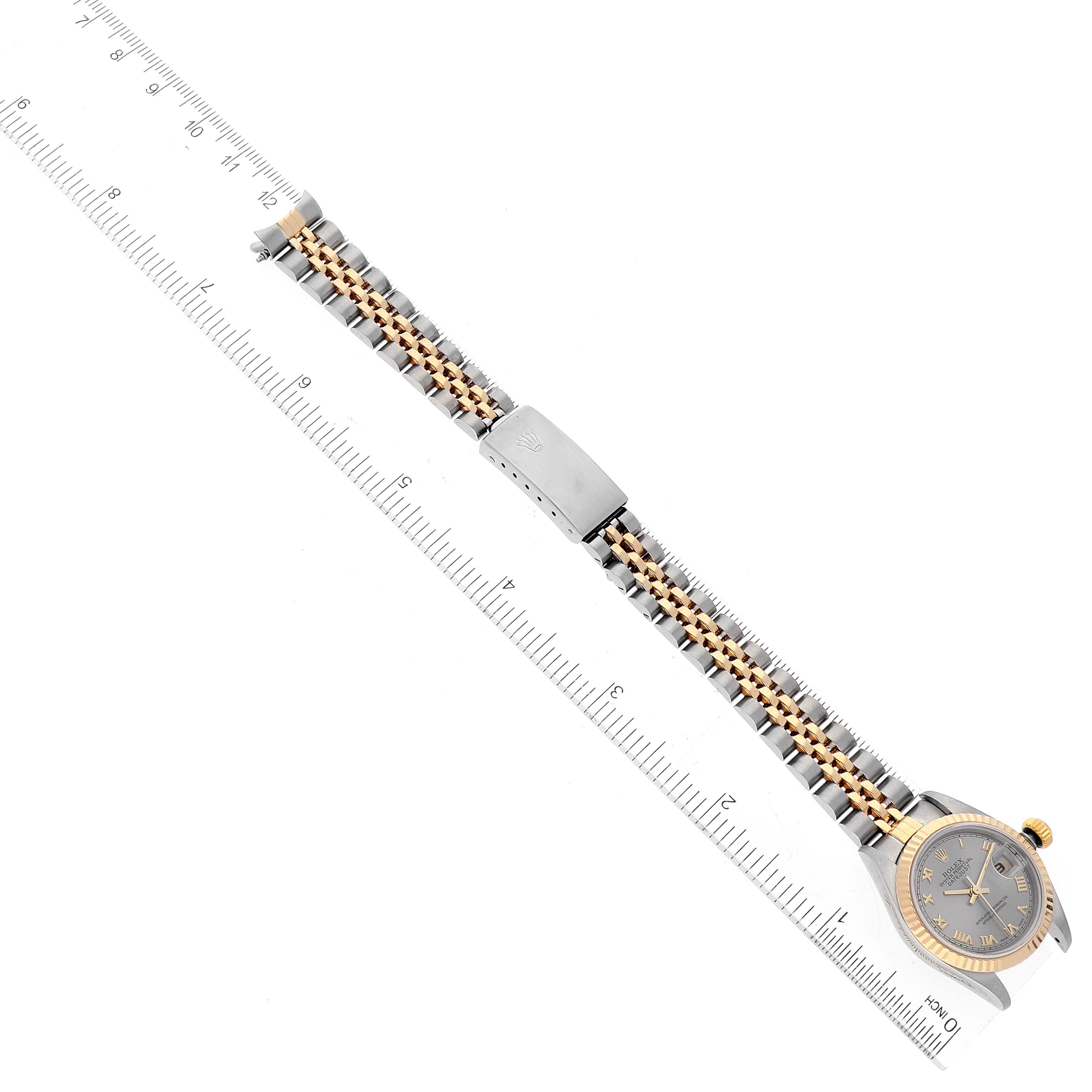 The image shows a Rolex Datejust 79173 Women
s Steel and Gold (two tone) Grey Dial 79173 Women
s Steel and Gold (two tone) Grey Dial watch displayed from a top angle, including the entire bracelet and part of a ruler for measurement.