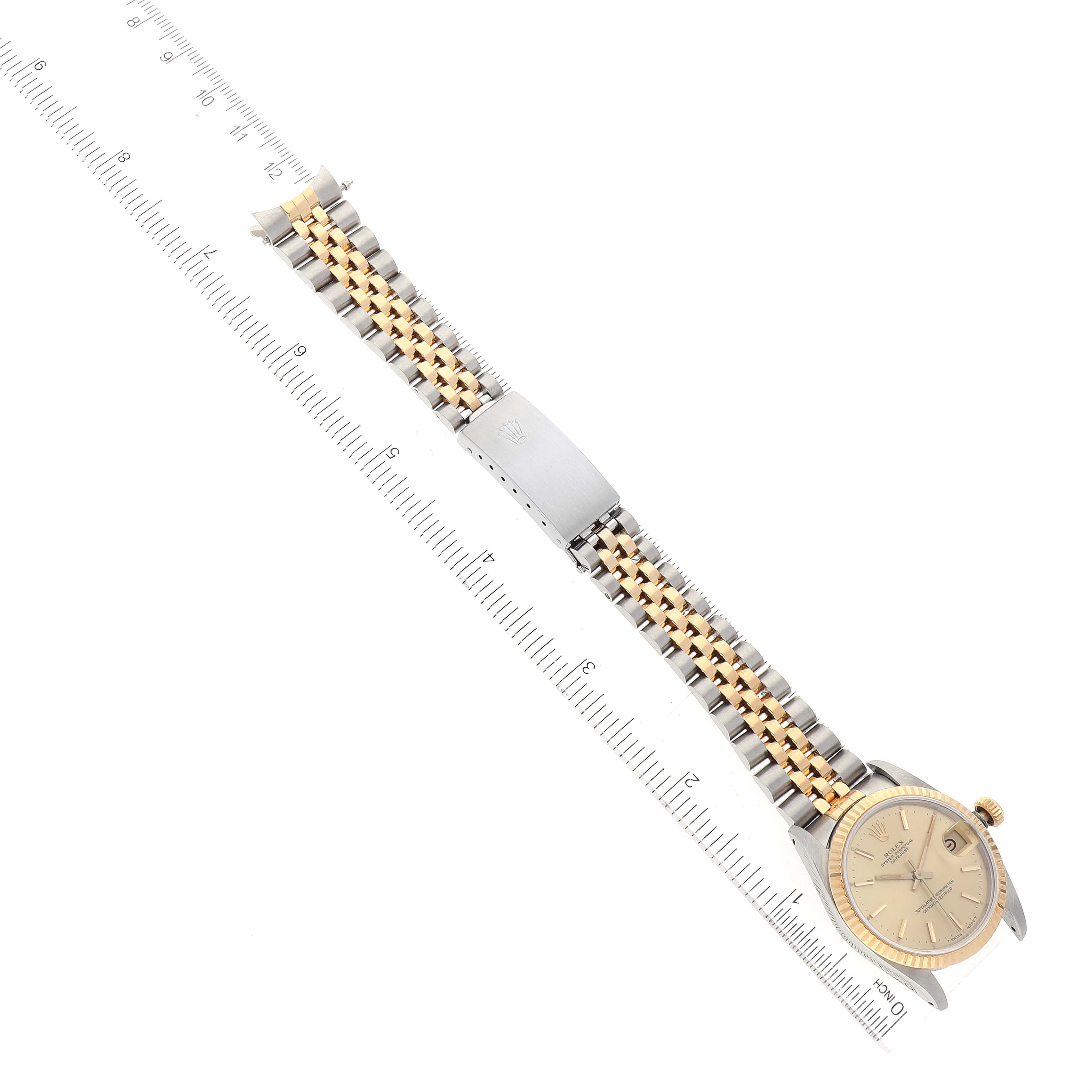 This image shows a top-down view of a Rolex Mid-Size 68273 Women
s Steel and Gold (two tone) Champagne Dial 68273 Women
s Steel and Gold (two tone) Champagne Dial watch, highlighting its two-tone bracelet, clasp, and face alongside a measuring scale.