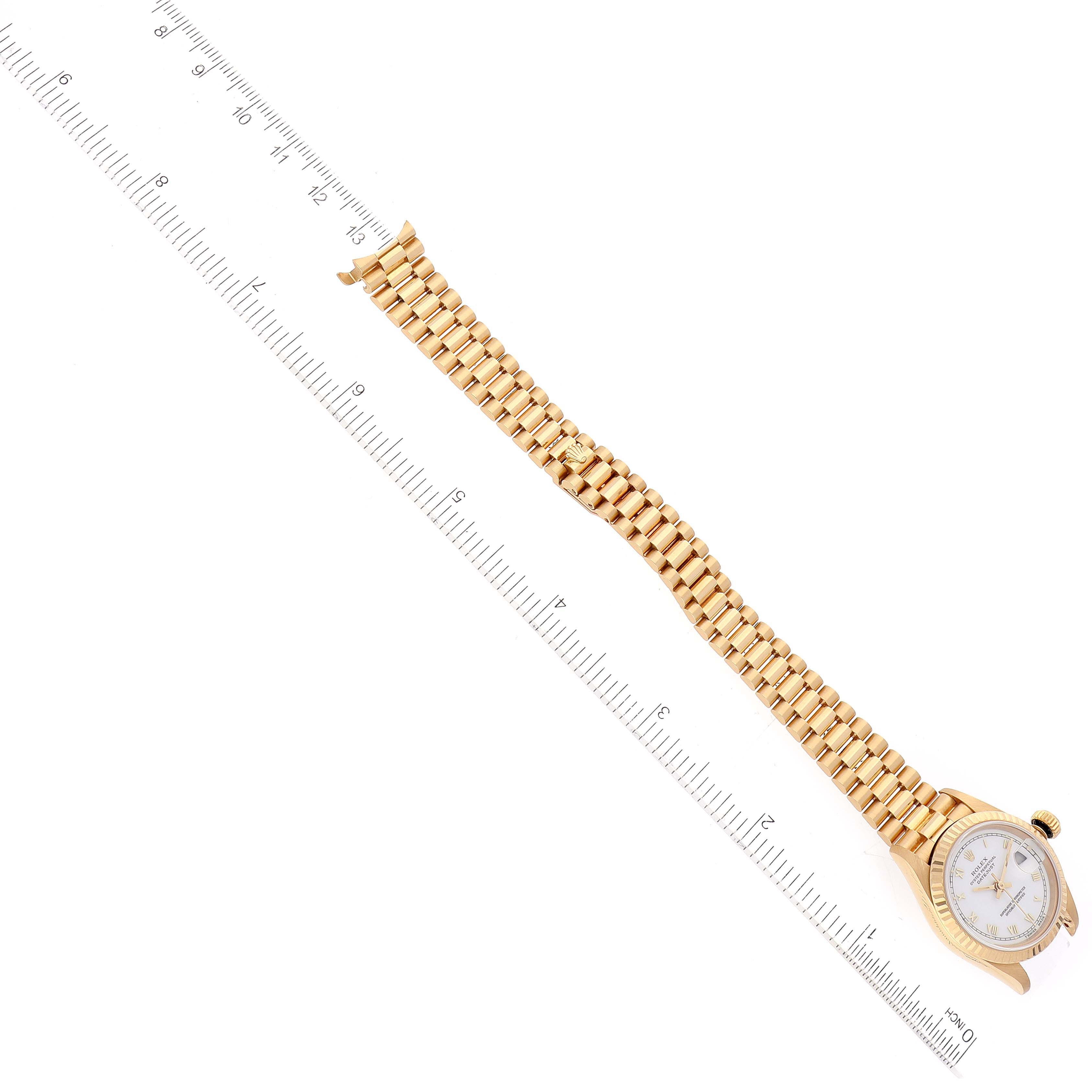 The image shows an overhead view of a Rolex President 69178 Women's Yellow Gold White Dial 69178 Women's Yellow Gold White Dial model watch with the dial, bracelet, and a ruler for scale.