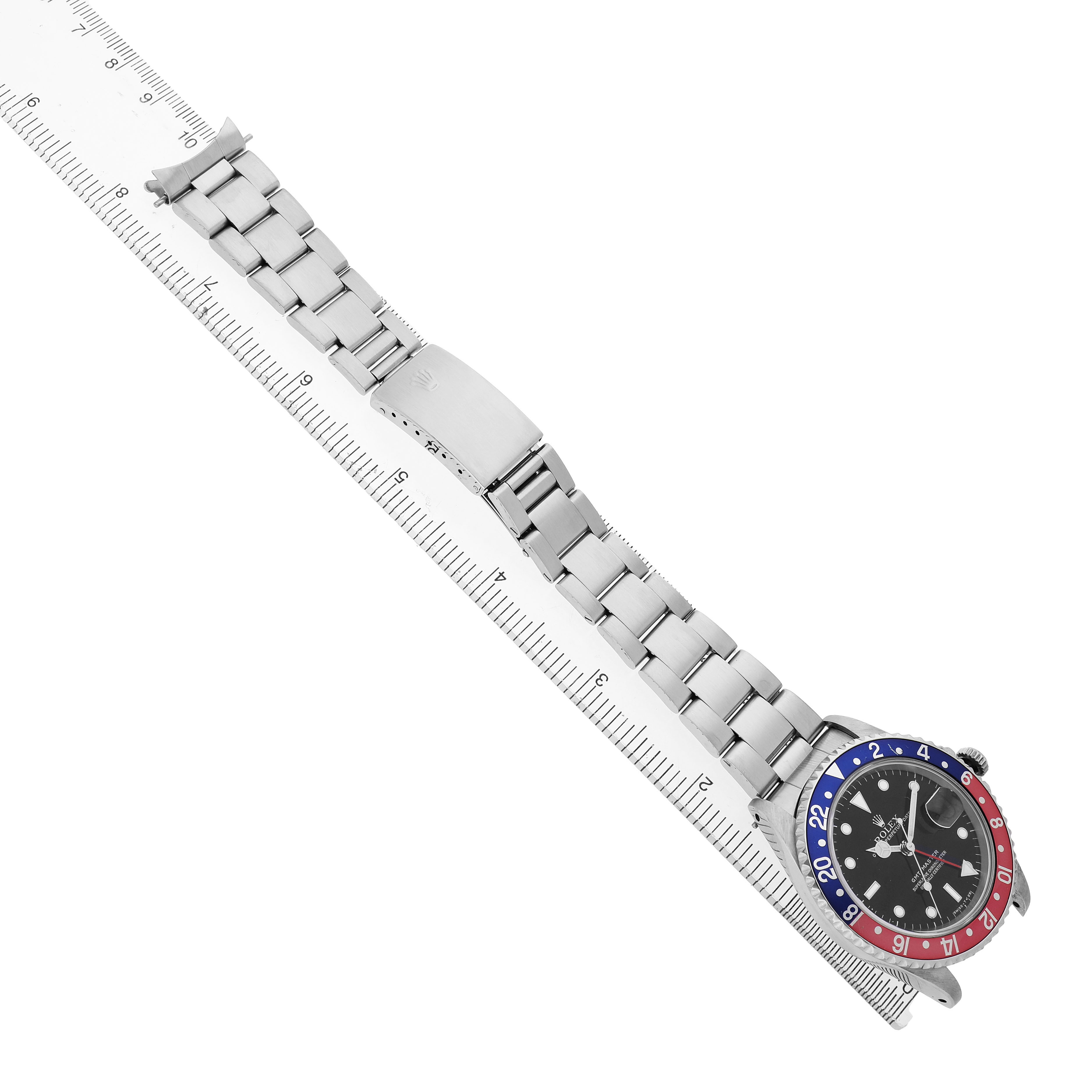 The Rolex GMT-Master 16700 Men's Stainless Steel Black Dial watch is shown from the side, displaying the bezel, dial, bracelet, and clasp alongside a ruler for scale.