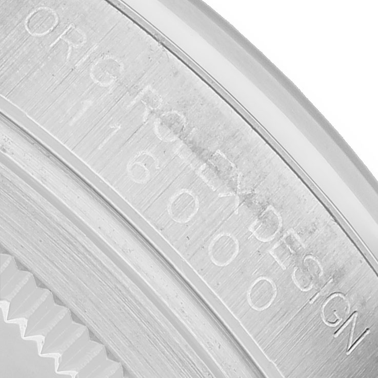 The image shows a close-up of the engraved inner bezel of a Rolex Oyster Perpetual 116000 Men's Stainless Steel Black Dial watch.
