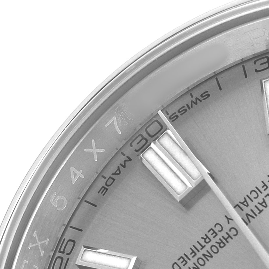 The close-up shows part of the dial and bezel of a Rolex Oyster Perpetual 116000 Men's Stainless Steel Silver Dial, highlighting the "Swiss Made" text and time markers.