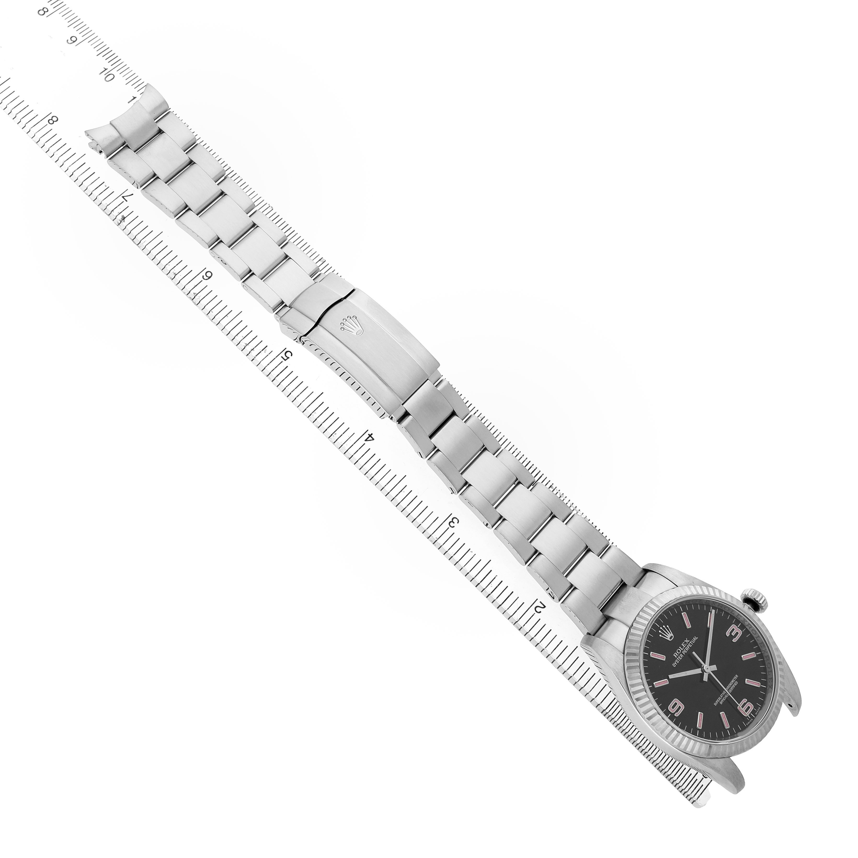 The Rolex Oyster Perpetual 116034 Men's Stainless Steel Black Dial watch is shown at an angle, highlighting the bracelet and clasp aligned along a ruler.
