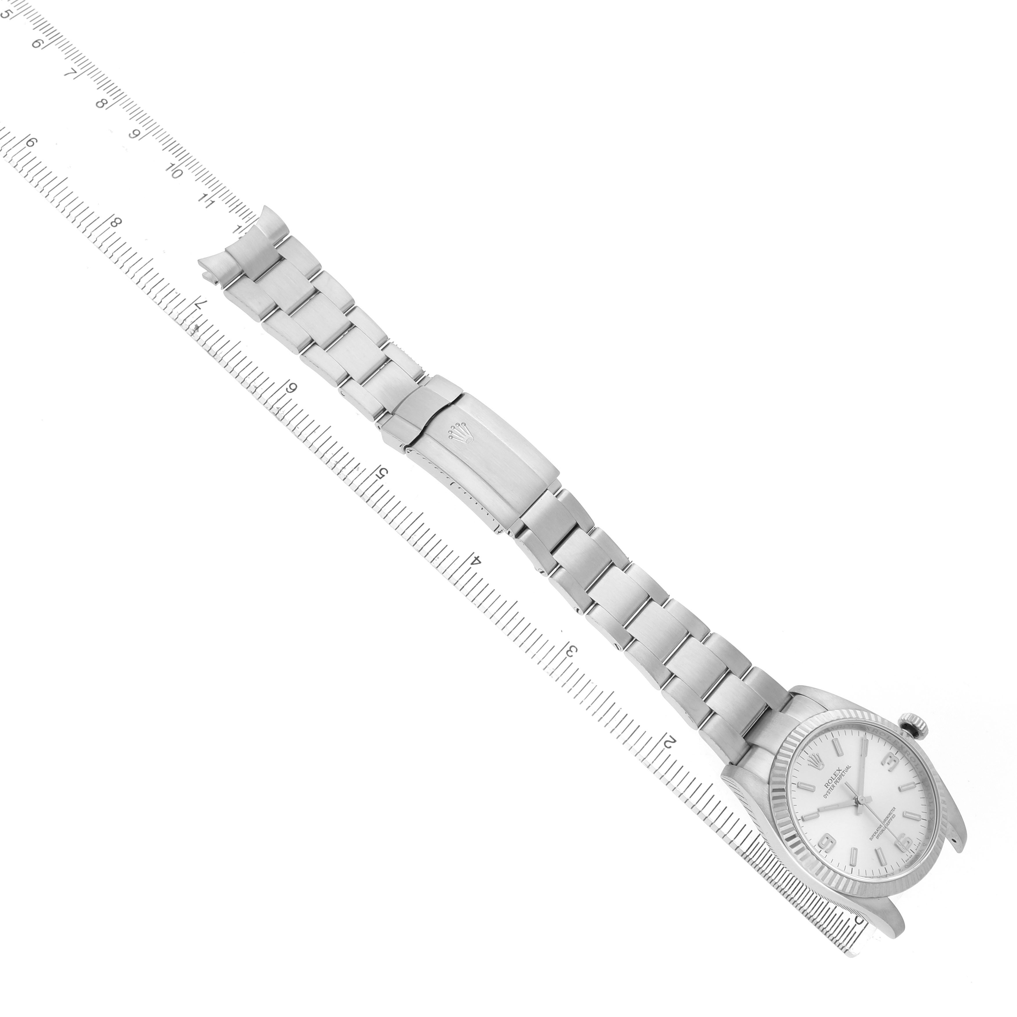 The Rolex Oyster Perpetual 116034 Men's Stainless Steel Silver Dial watch is shown from a top-down angle, highlighting the watch face, bracelet, and clasp along a ruler.