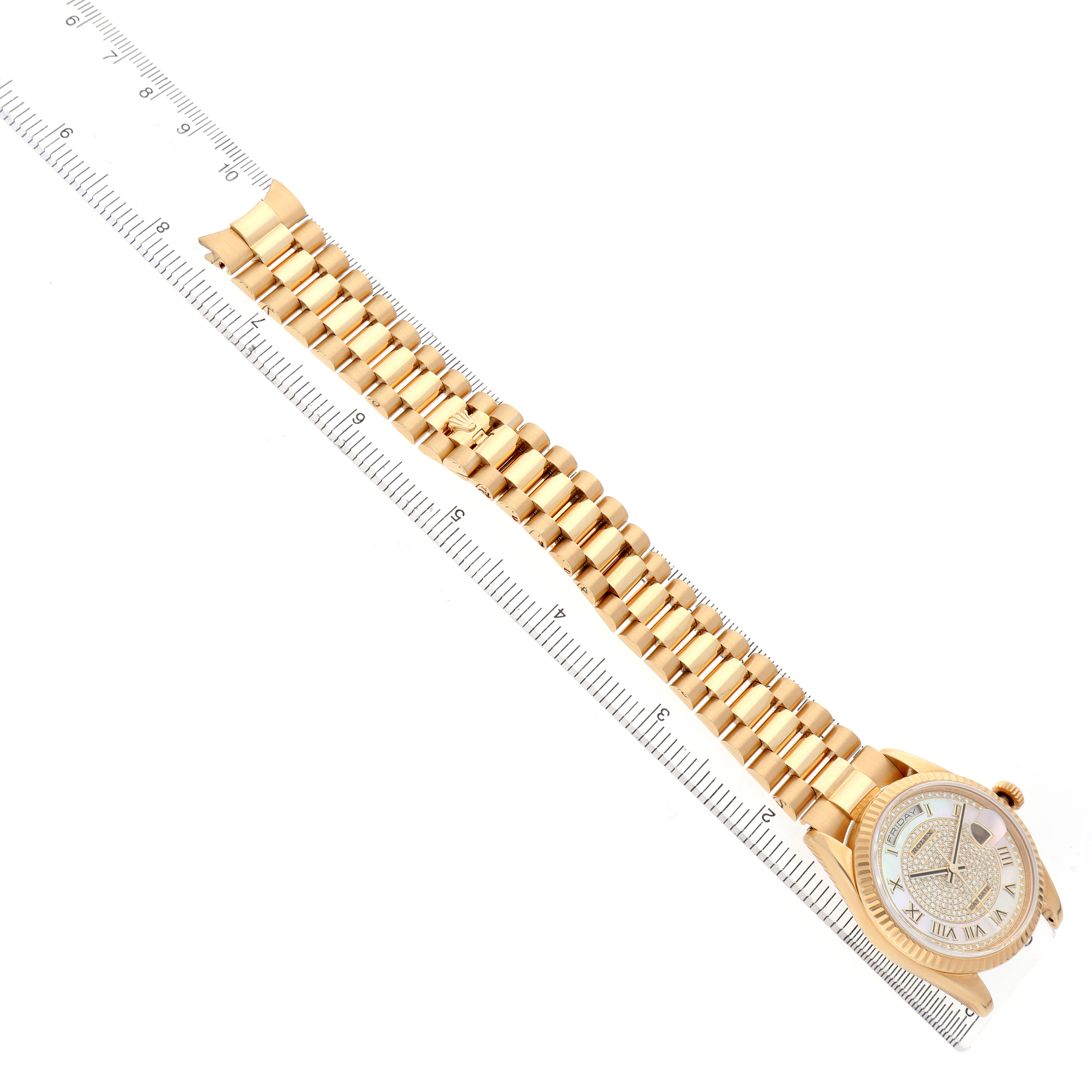 The image shows a Rolex President 118238 Men's Yellow Gold Mother of Pearl Dial model watch from a top view, featuring its dial, bezel, and bracelet laid next to a ruler.