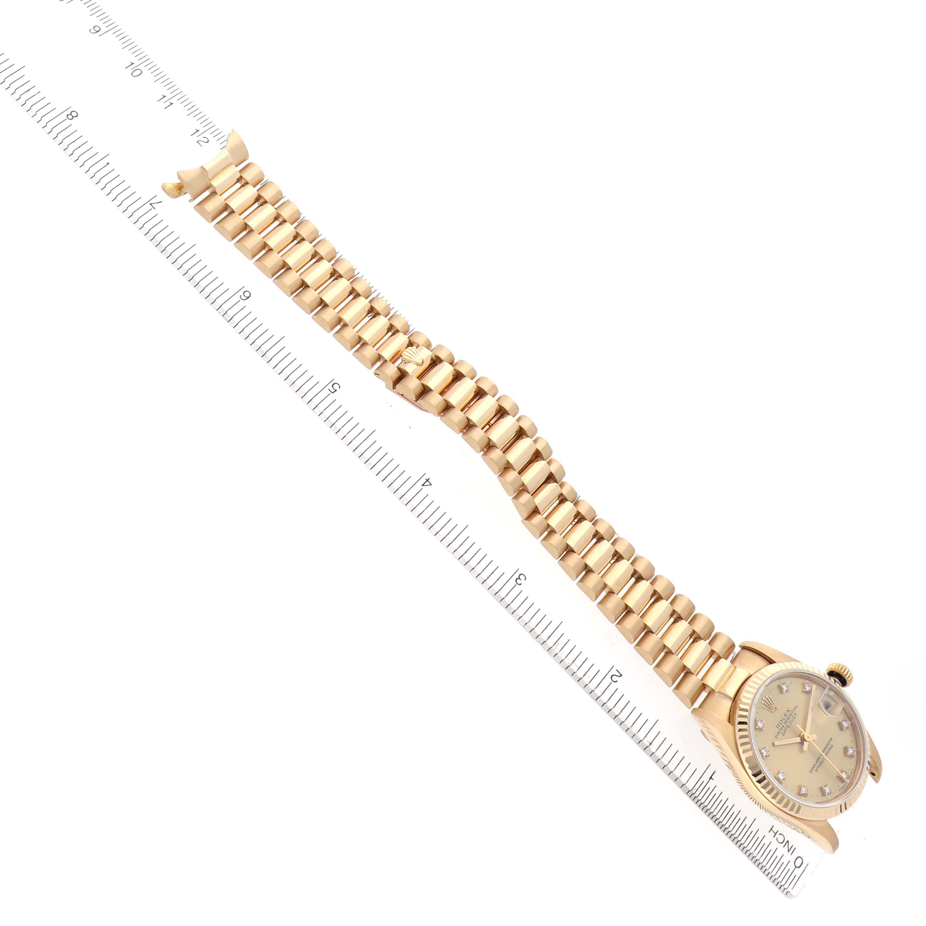 The Rolex President 68278 Women's Yellow Gold Champagne Dial model watch is shown from an angled top view, displaying its dial and bracelet alongside a ruler for scale.