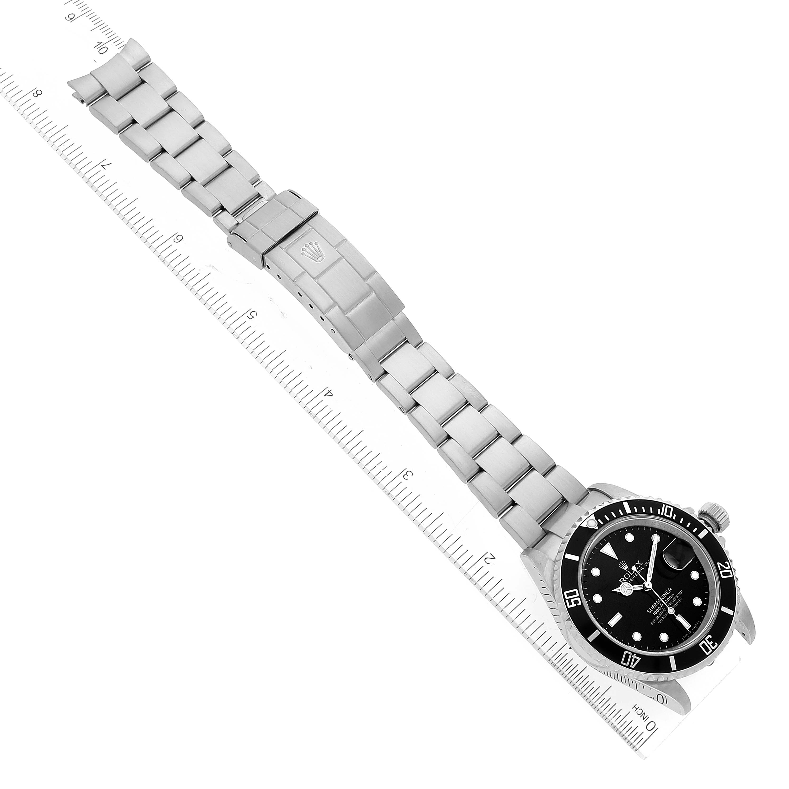 The image shows a Rolex Submariner 16610 Men
s Stainless Steel Black Dial 16610 Men
s Stainless Steel Black Dial watch laid flat alongside a ruler, displaying the face, bezel, bracelet, and clasp.