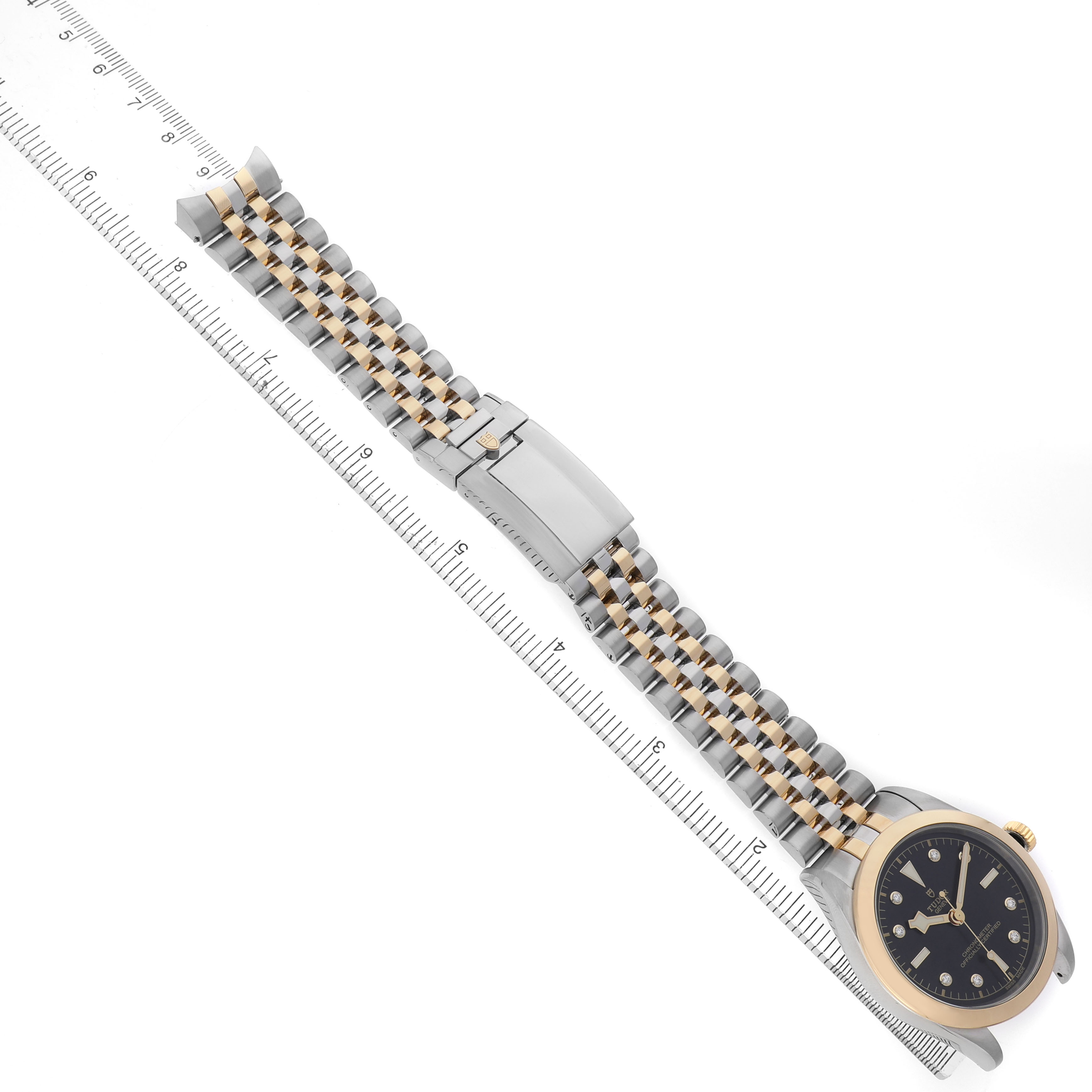 The Tudor Heritage Black Bay 79663 Men's Steel and Gold (two tone) Black Dial watch is shown at an oblique angle, displaying the face, bracelet, and clasp.