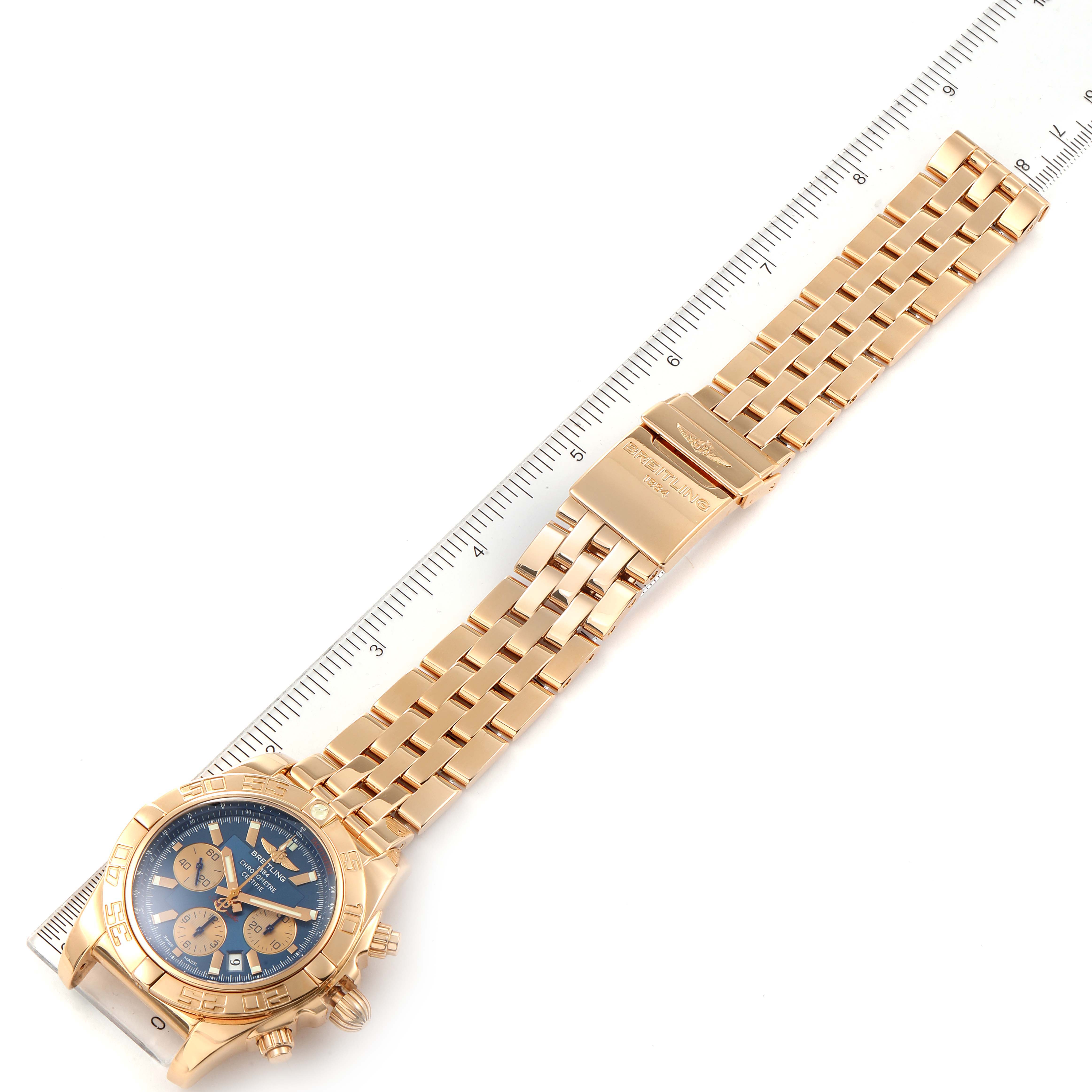 The image shows a top-down view of a Breitling Chronomat HB0110 Men's Rose Gold Blue Dial HB0110 Men's Rose Gold Blue Dial watch, highlighting the face, bezel, and metal bracelet with a ruler for scale.