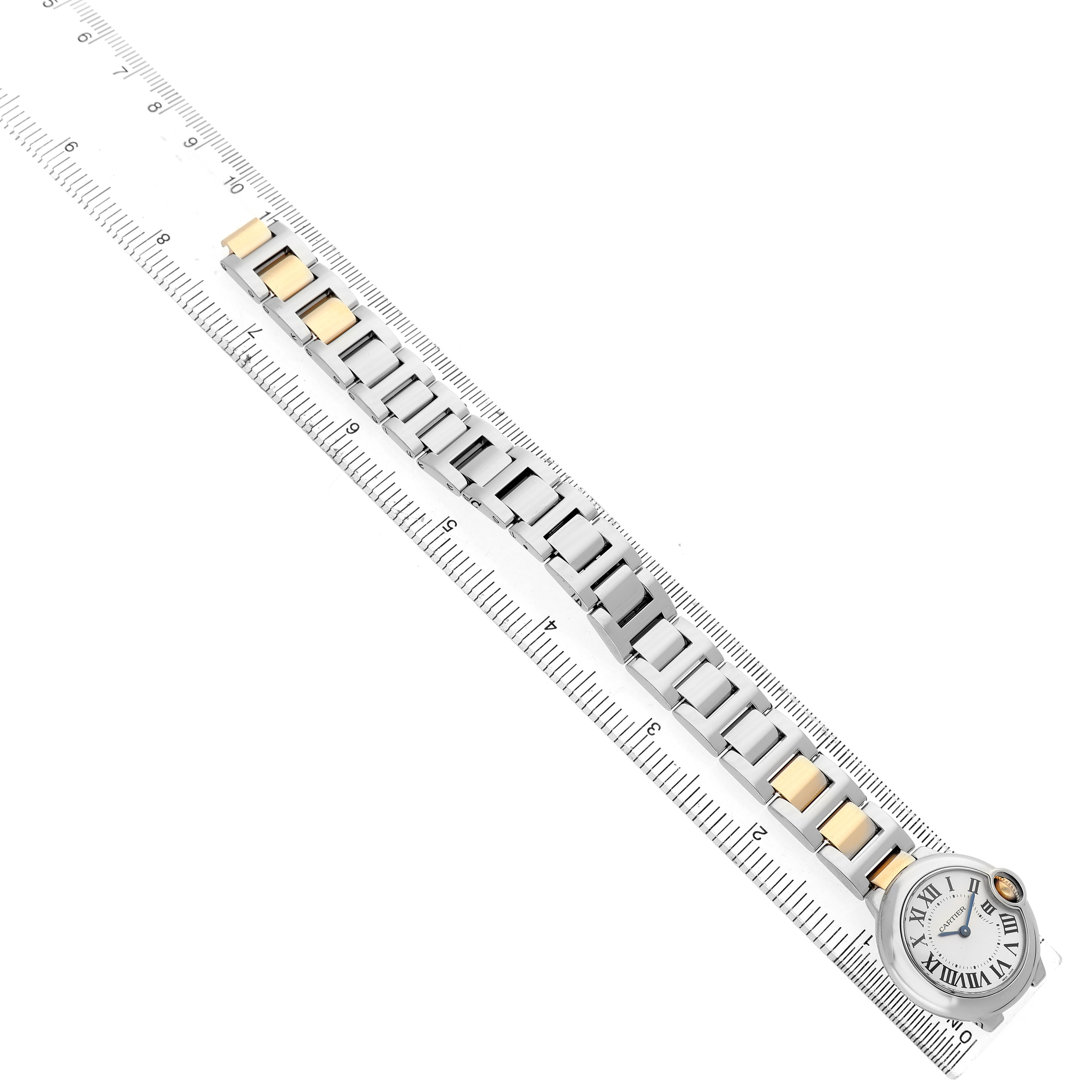 The Cartier Ballon Bleu W69007Z3 Women's Steel and Gold (two tone) Silver Dial watch is shown from a top-down angle, highlighting its face and metal bracelet on a ruler.