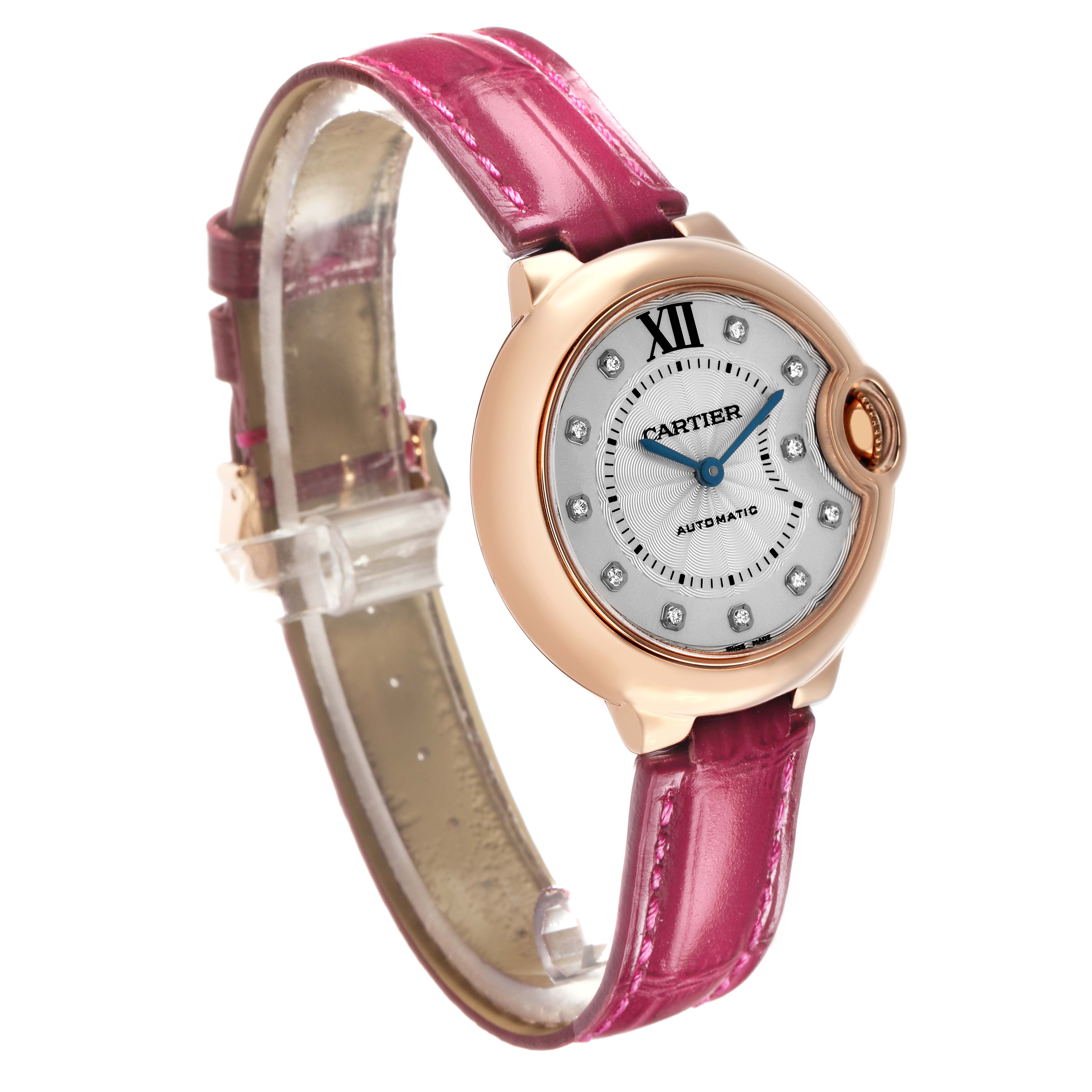 The Cartier Ballon Bleu WE902063 Women's Rose Gold Silver Dial watch is shown from a side angle, highlighting its round face, pink leather strap, and distinctive crown.
