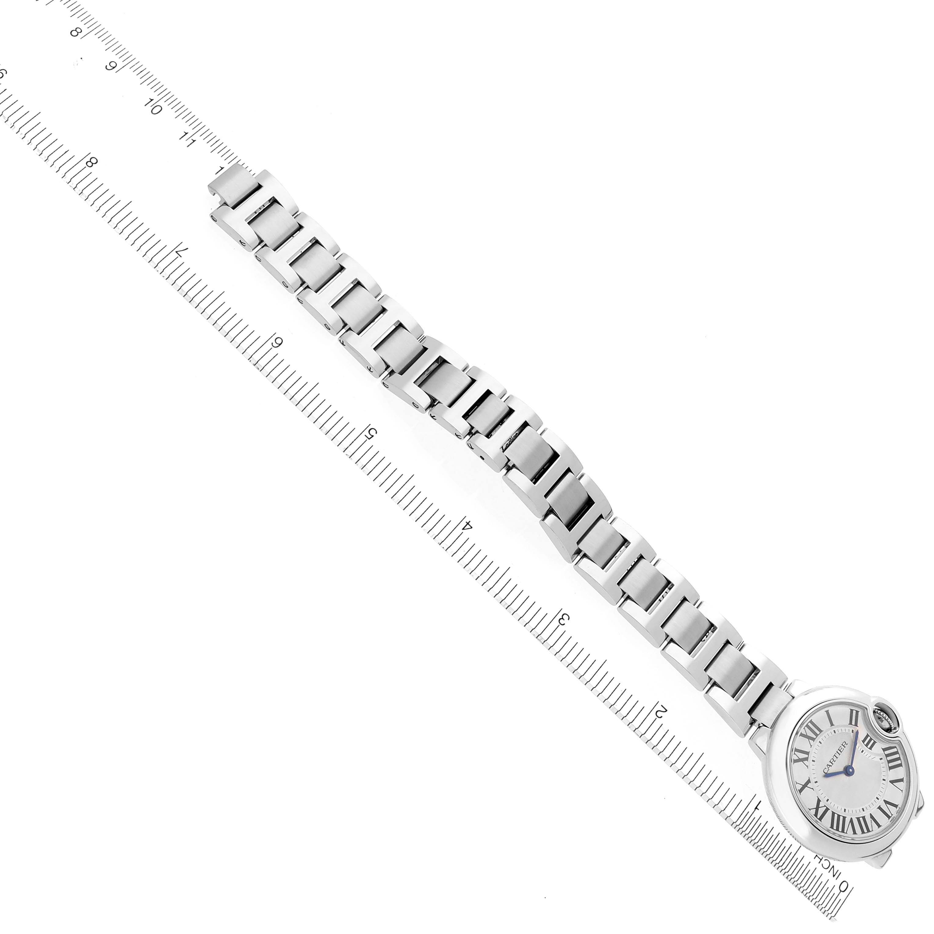 The image shows a top view of a Cartier Ballon Bleu W6920084 Women's Stainless Steel Silver Dial W6920084 Women's Stainless Steel Silver Dial watch with a metal bracelet and dial next to a ruler.