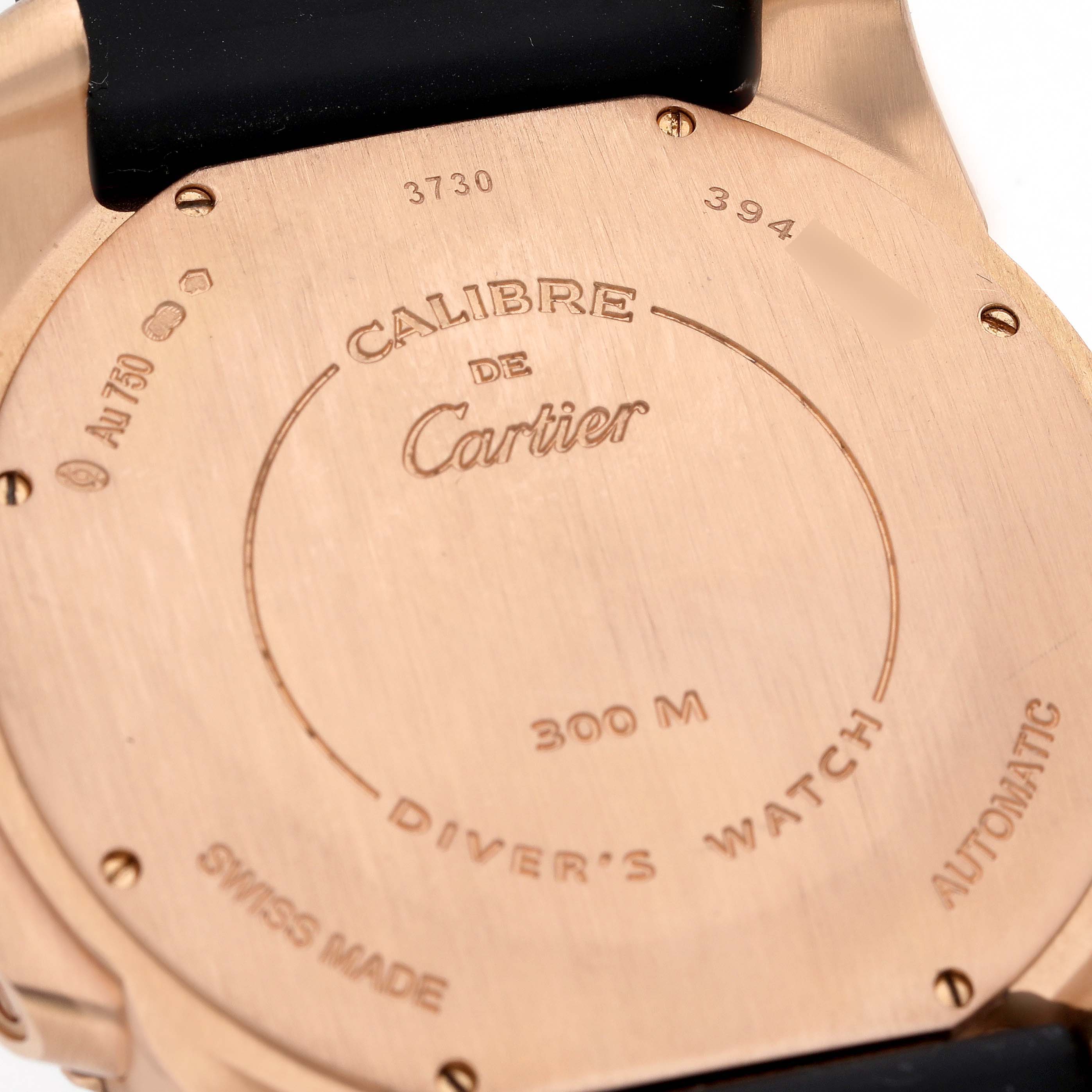 The image shows the back case of a Calibre de Cartier watch by Cartier, highlighting its engravings and seals.